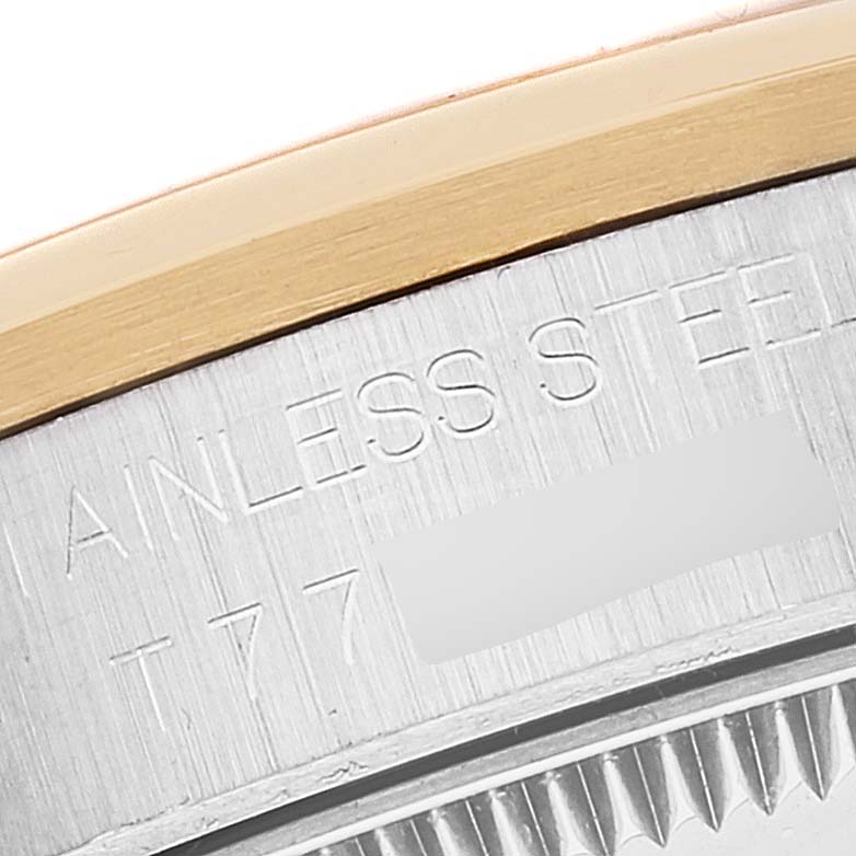 This close-up image shows the stainless steel case back edge and part of the gold bezel of a mid-size Rolex watch.