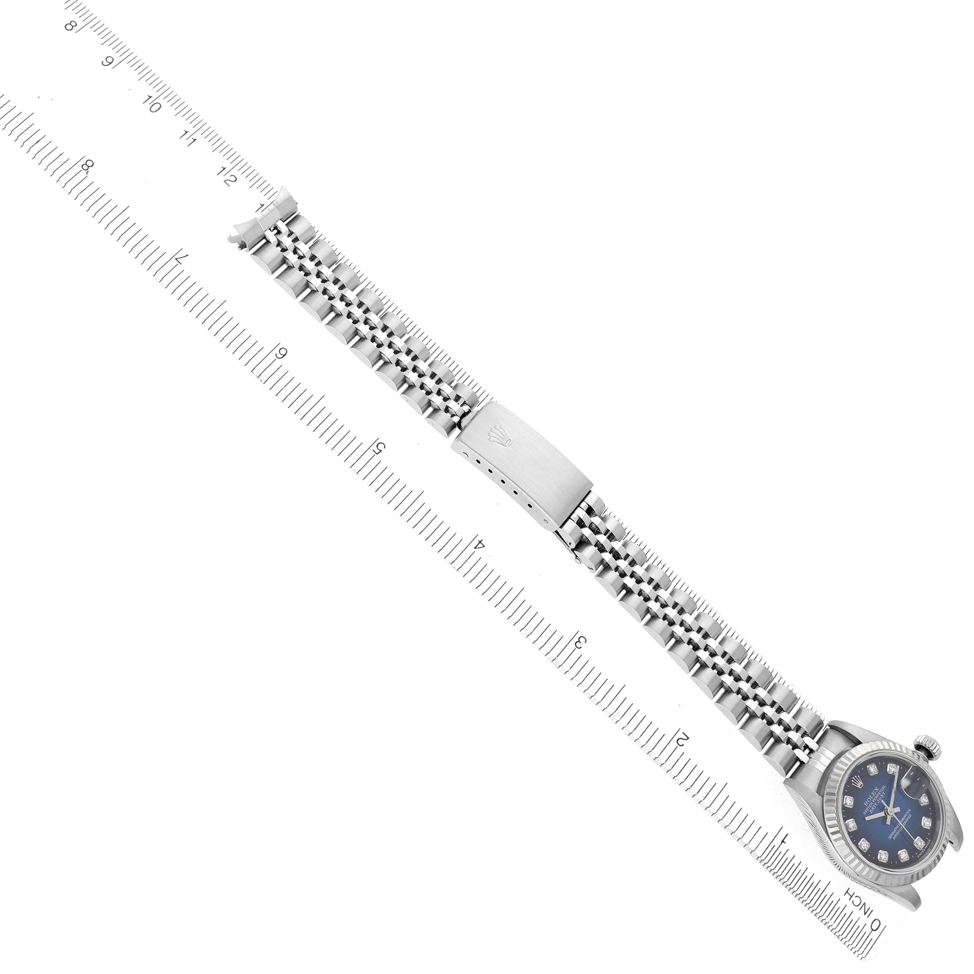 The Rolex Datejust 69174 Women's Stainless Steel Blue Dial 69174 Women's Stainless Steel Blue Dial watch is shown from a side angle with a focus on its bracelet and crown, placed diagonally on a ruler.