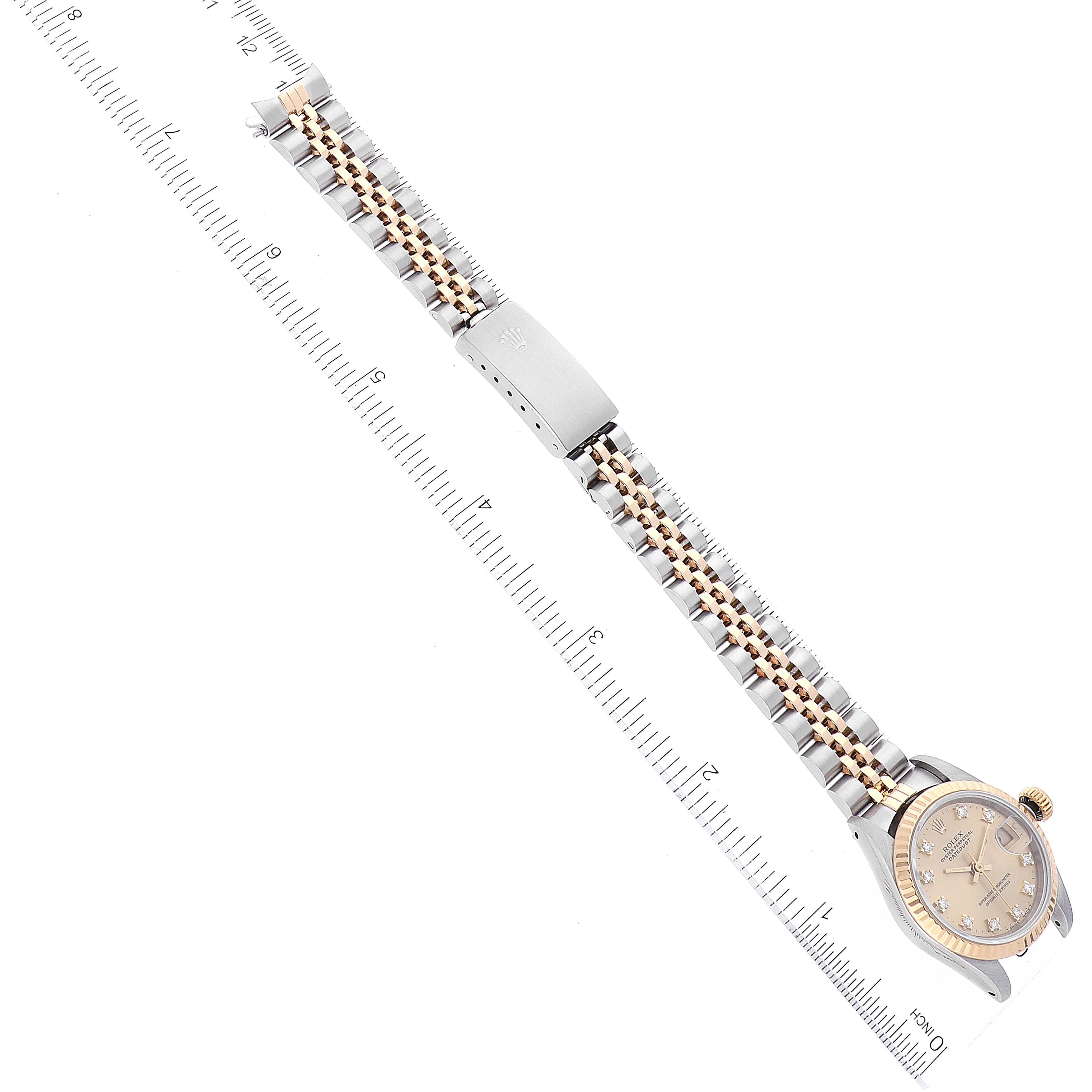 This image shows a Rolex Datejust 69173 Women's Steel and Gold (two tone) Champagne Dial 69173 Women's Steel and Gold (two tone) Champagne Dial watch horizontally with its face, bracelet, and clasp visible alongside a ruler.