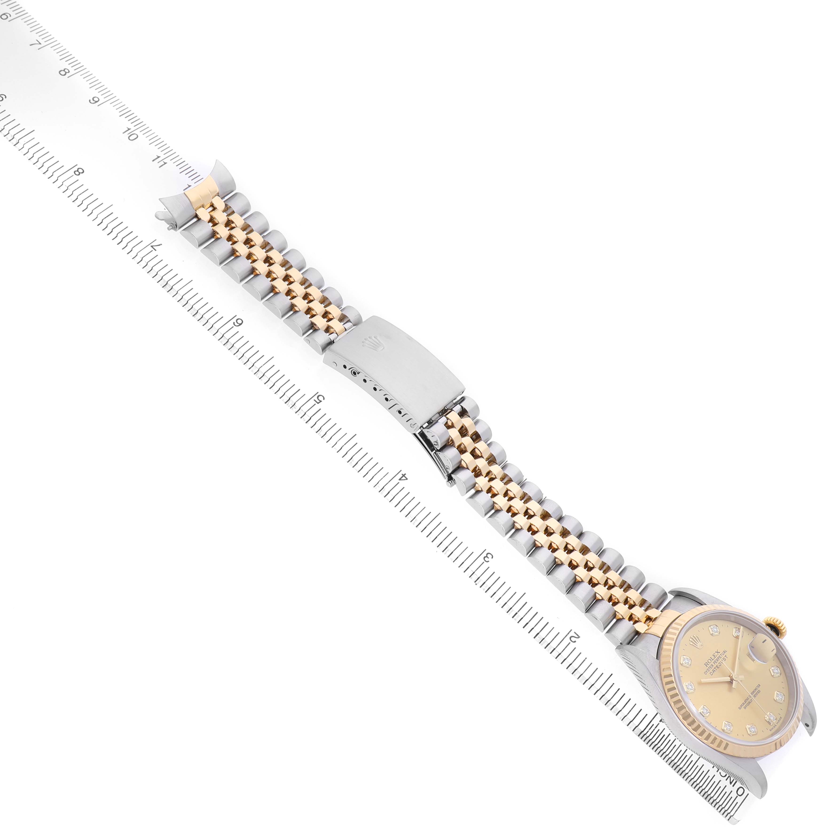 The image shows a Rolex Datejust 16233 Men's Steel and Gold (two tone) Champagne Dial watch laid diagonally, highlighting its bracelet, clasp, and face beside a ruler.