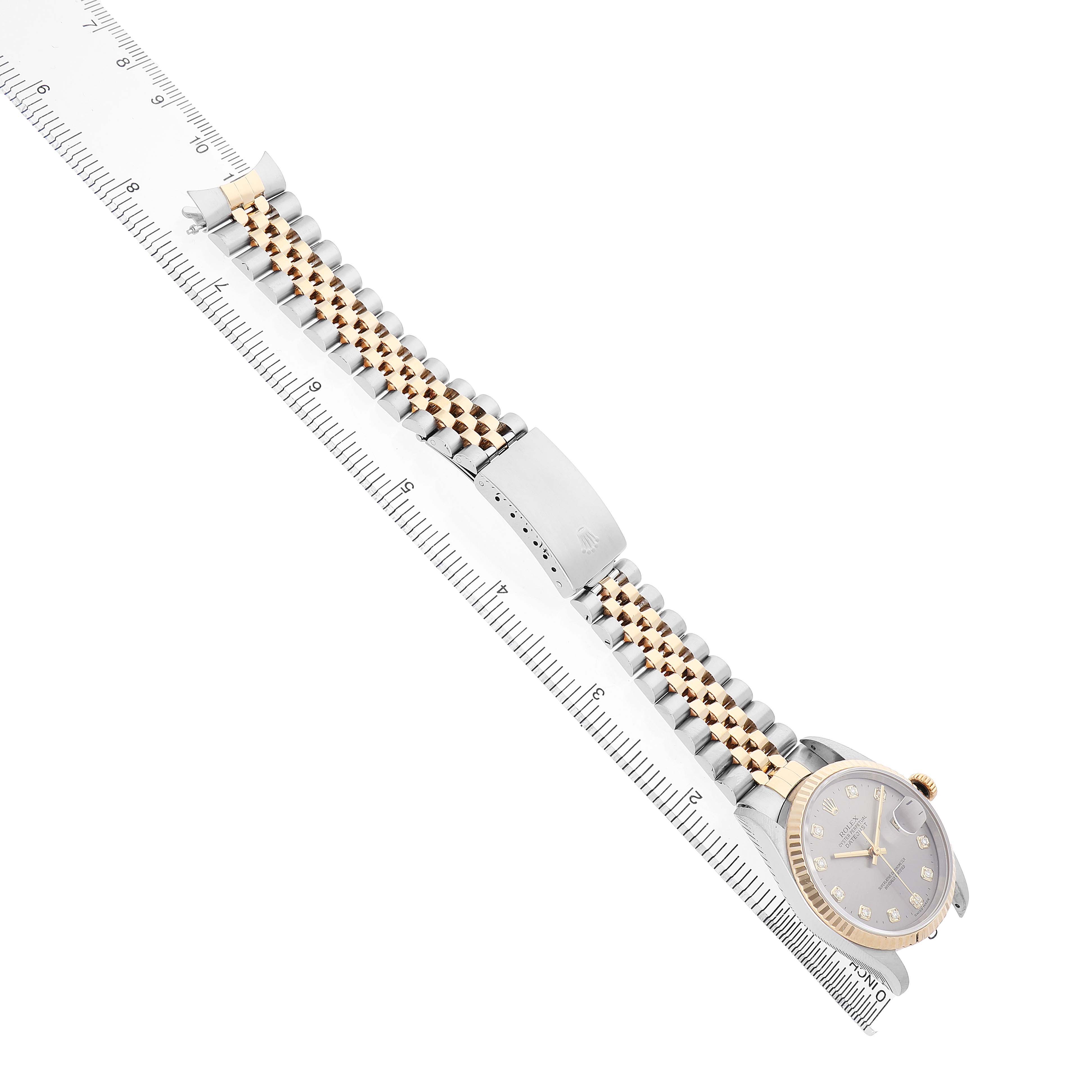 The Rolex Datejust 16233 Men's Steel and Gold (two tone) Silver Dial watch is shown from a side angle, displaying the face, bracelet, and clasp alongside a ruler.