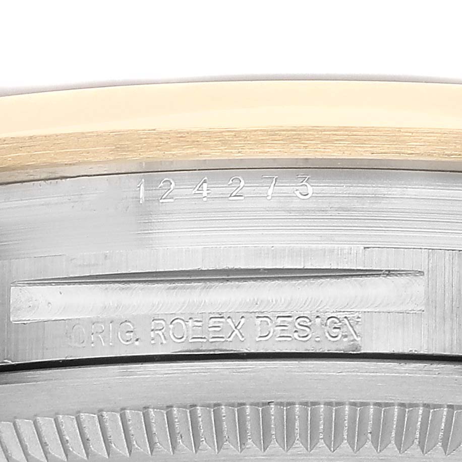 The image shows the case side and edge of a Rolex Explorer 124273 Men's Steel and Gold (two tone) Black Dial, focusing on engravings and the bezel detail.