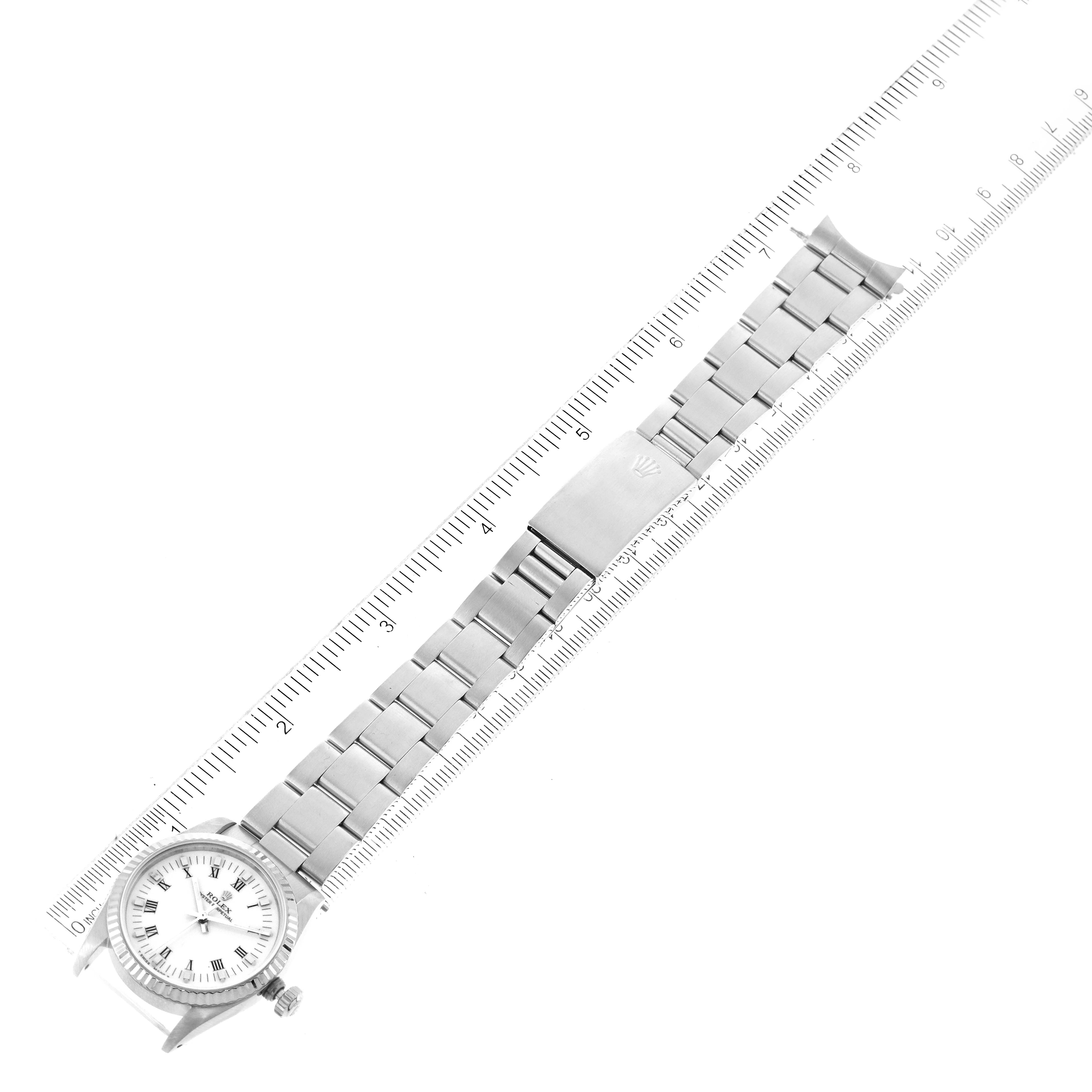 The image shows a horizontally laid out Rolex Mid-Size 67514 Women
s Stainless Steel White Dial 67514 Women
s Stainless Steel White Dial watch with its stainless steel bracelet next to a ruler for scale.