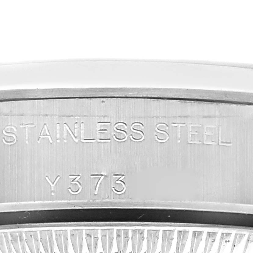 The image shows a close-up of the Rolex Oyster Perpetual 76080 Women's Stainless Steel Black Dial 76080 Women's Stainless Steel Black Dial watch's stainless steel case back with engravings.