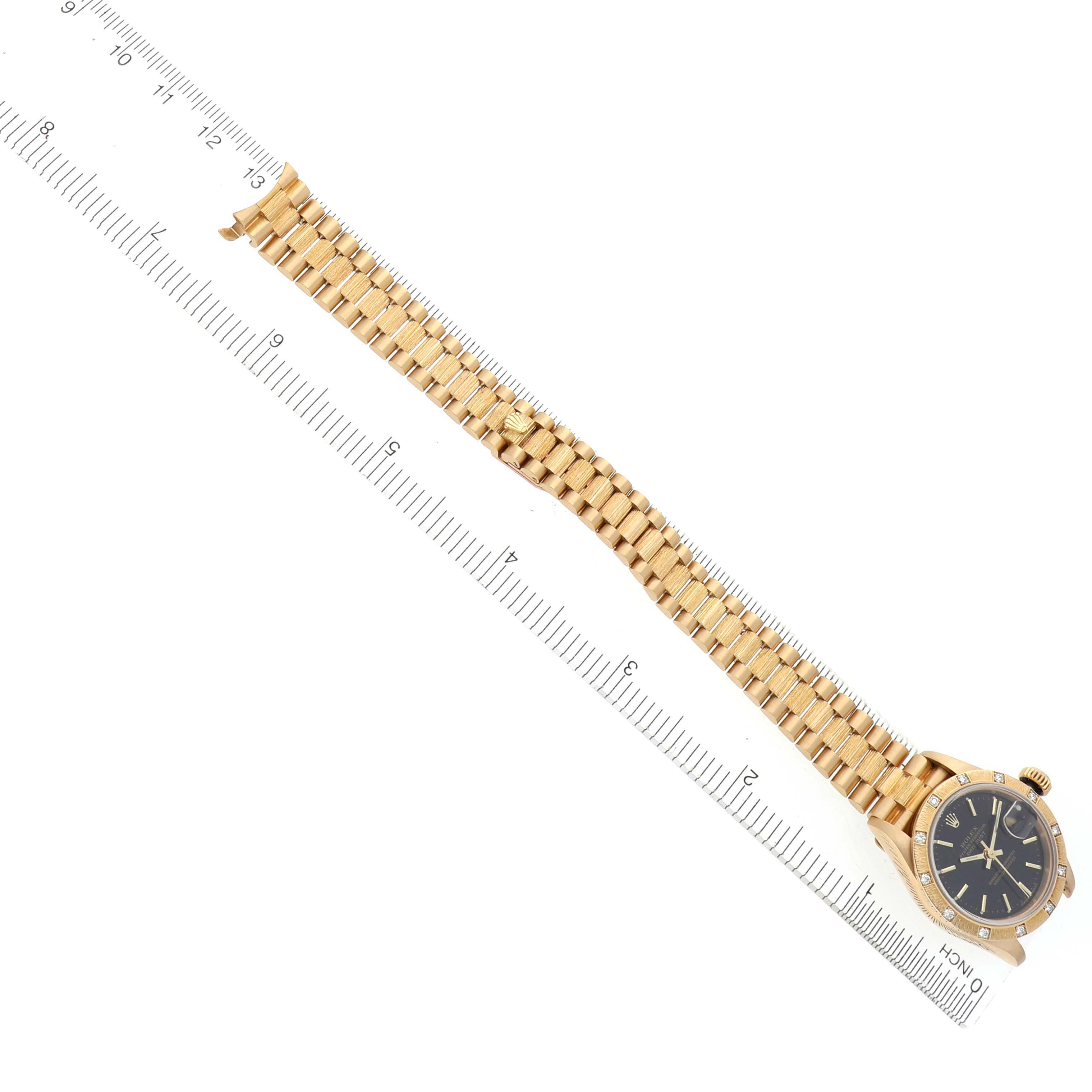 The image shows a Rolex President 69288 Women's Yellow Gold Black Dial 69288 Women's Yellow Gold Black Dial model watch laid flat, highlighting the bracelet and face alongside a ruler.