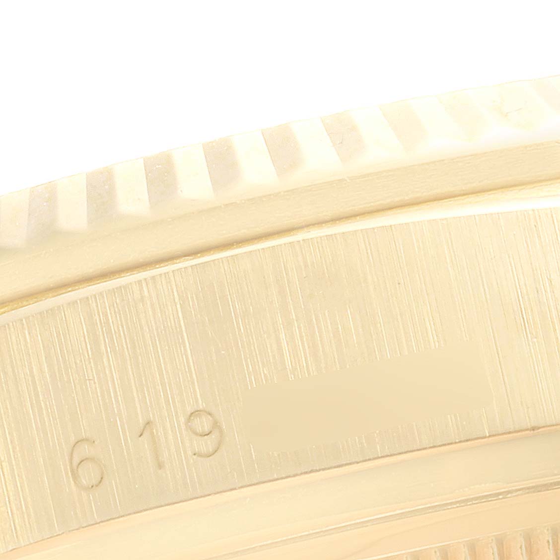 This close-up image of the Rolex President 18038 Men's Yellow Gold White Dial 18038 Men's Yellow Gold White Dial watch shows the fluted bezel and part of the case with engraved serial numbers.