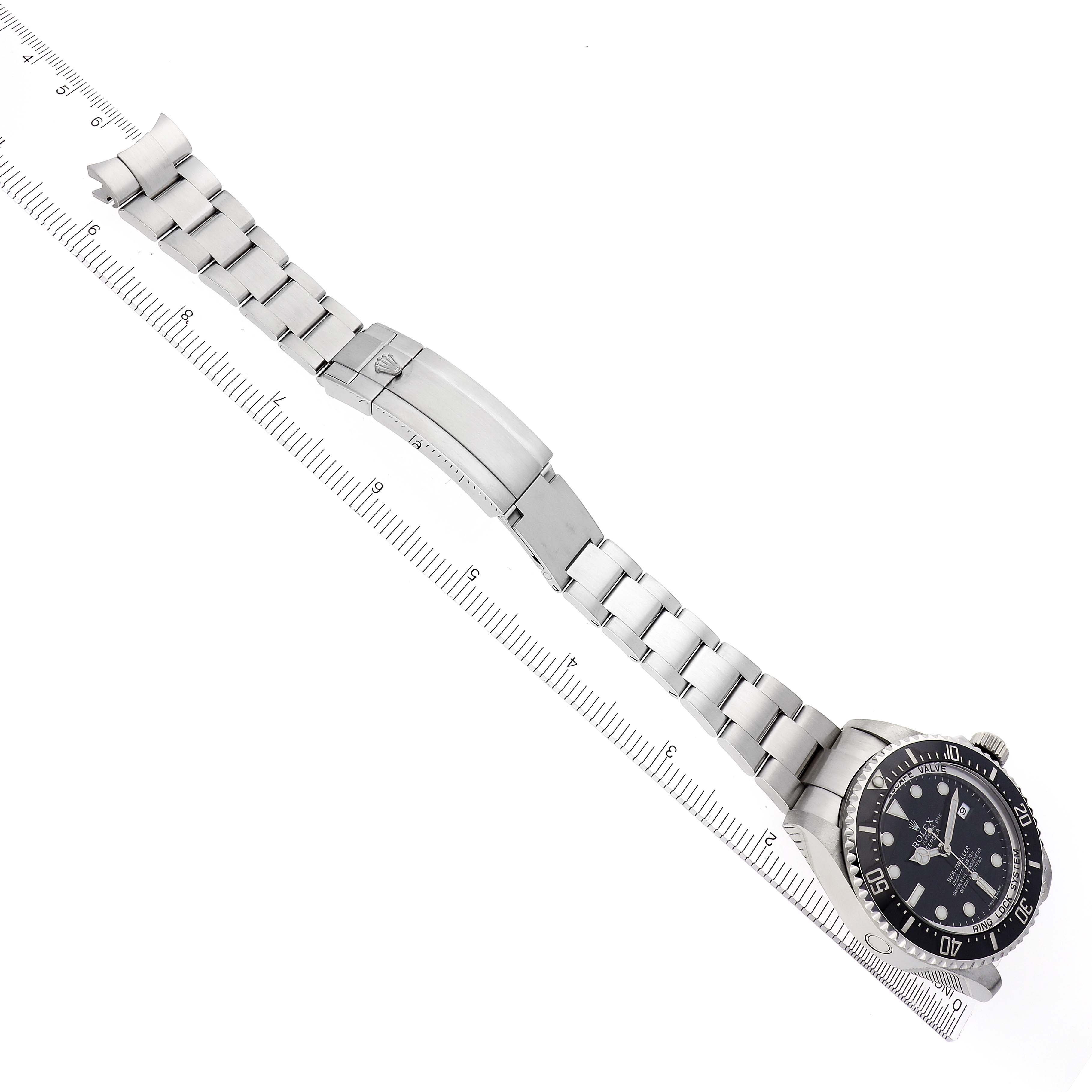 The Rolex Sea-Dweller 116660 Men's Stainless Steel Black Dial 116660 Men's Stainless Steel Black Dial watch is shown from a top-down angle, highlighting the face, bezel, bracelet, and clasp against a ruler.