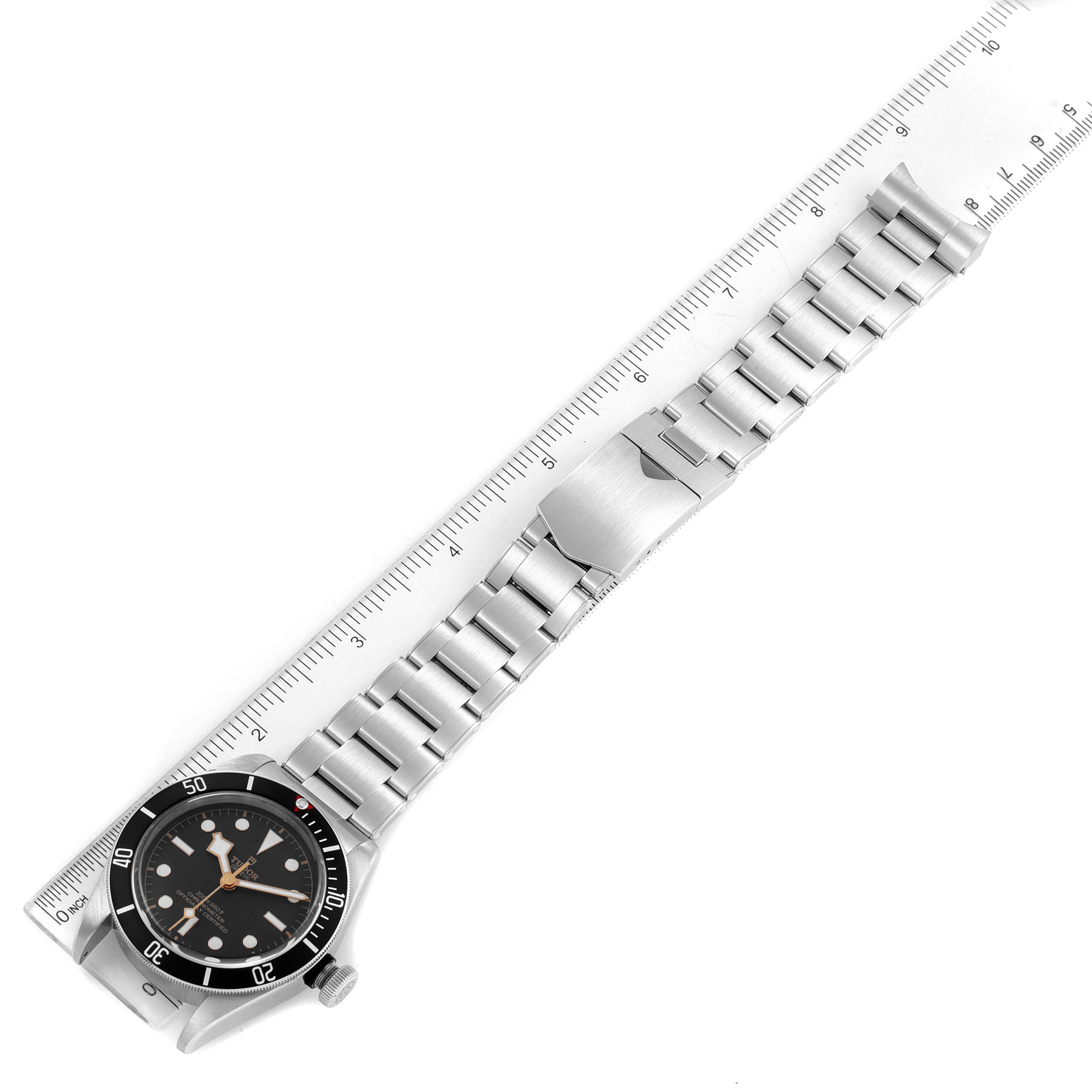 The image shows a top-down view of a Tudor Heritage Black Bay 79230 Men's Stainless Steel Black Dial 79230 Men's Stainless Steel Black Dial watch with a metal bracelet next to a ruler for scale.