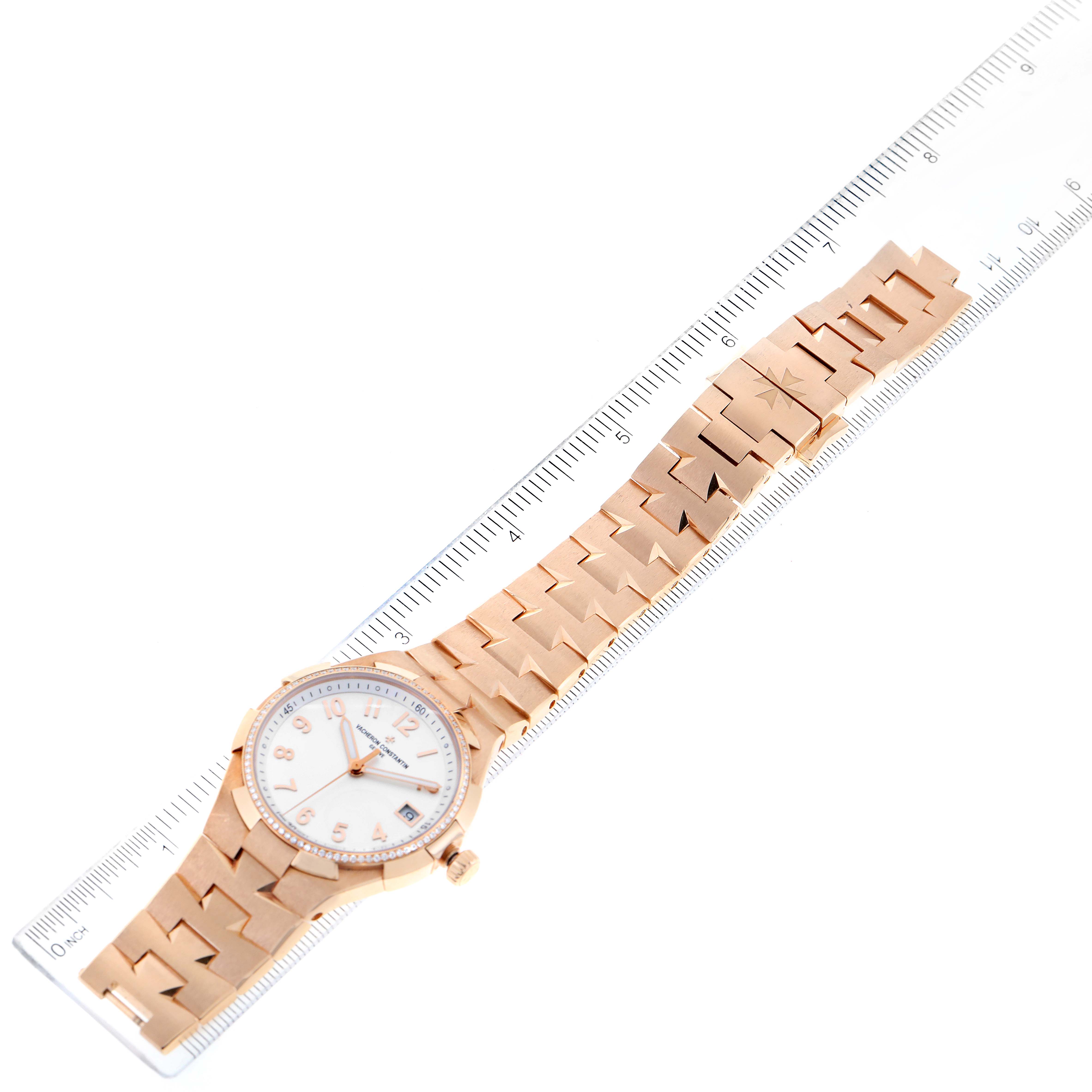 The image shows a top view of the Vacheron Constantin Overseas 47560/D01R-9672 Women's Rose Gold Silver Dial 47560/D01R-9672 Women's Rose Gold Silver Dial watch with its band extended next to a ruler for scale.