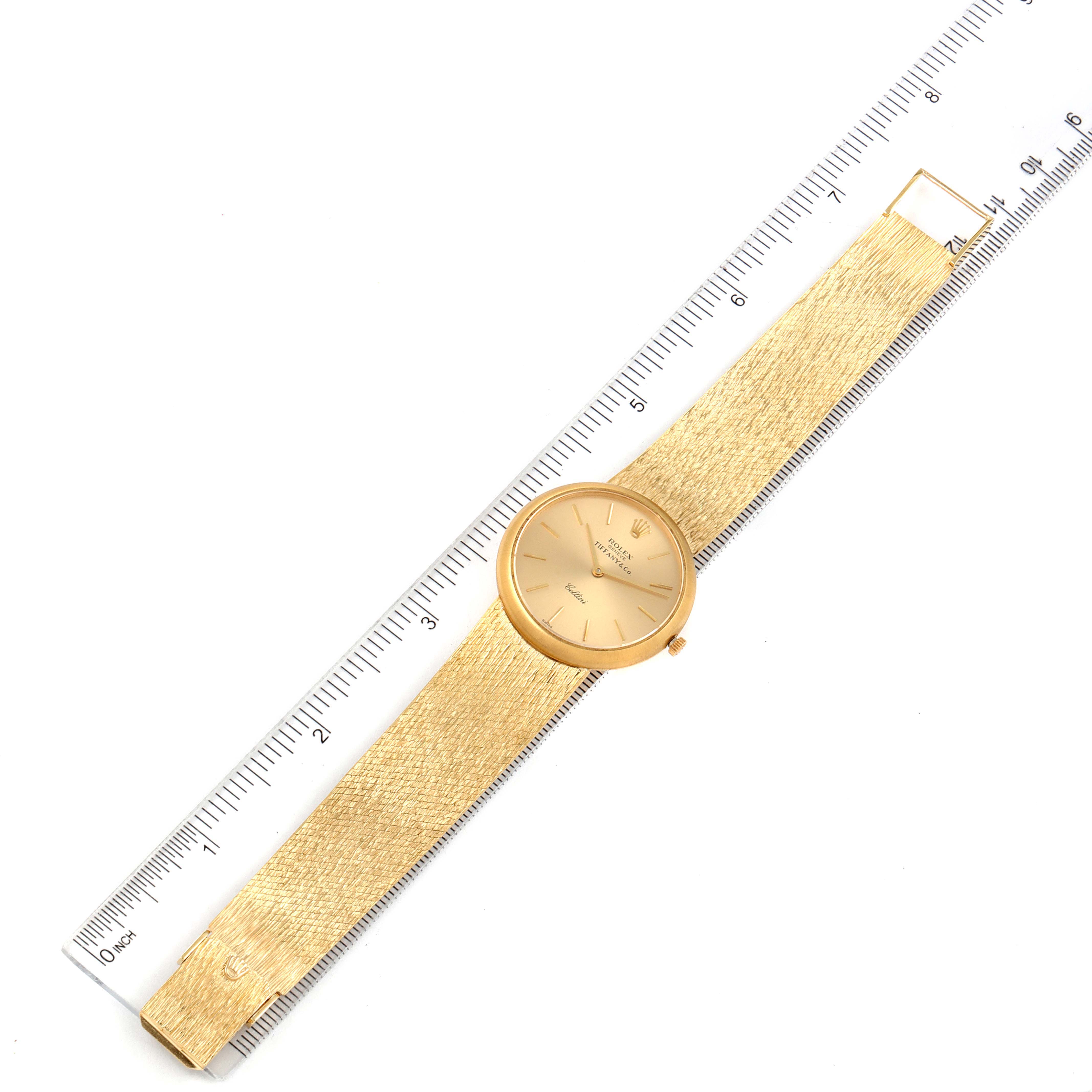 The Rolex Cellini Men's Yellow Gold Champagne Dial Men's Yellow Gold Champagne Dial watch is shown from a top-down angle, including its face, dial, and entire strap, next to a ruler for scale.