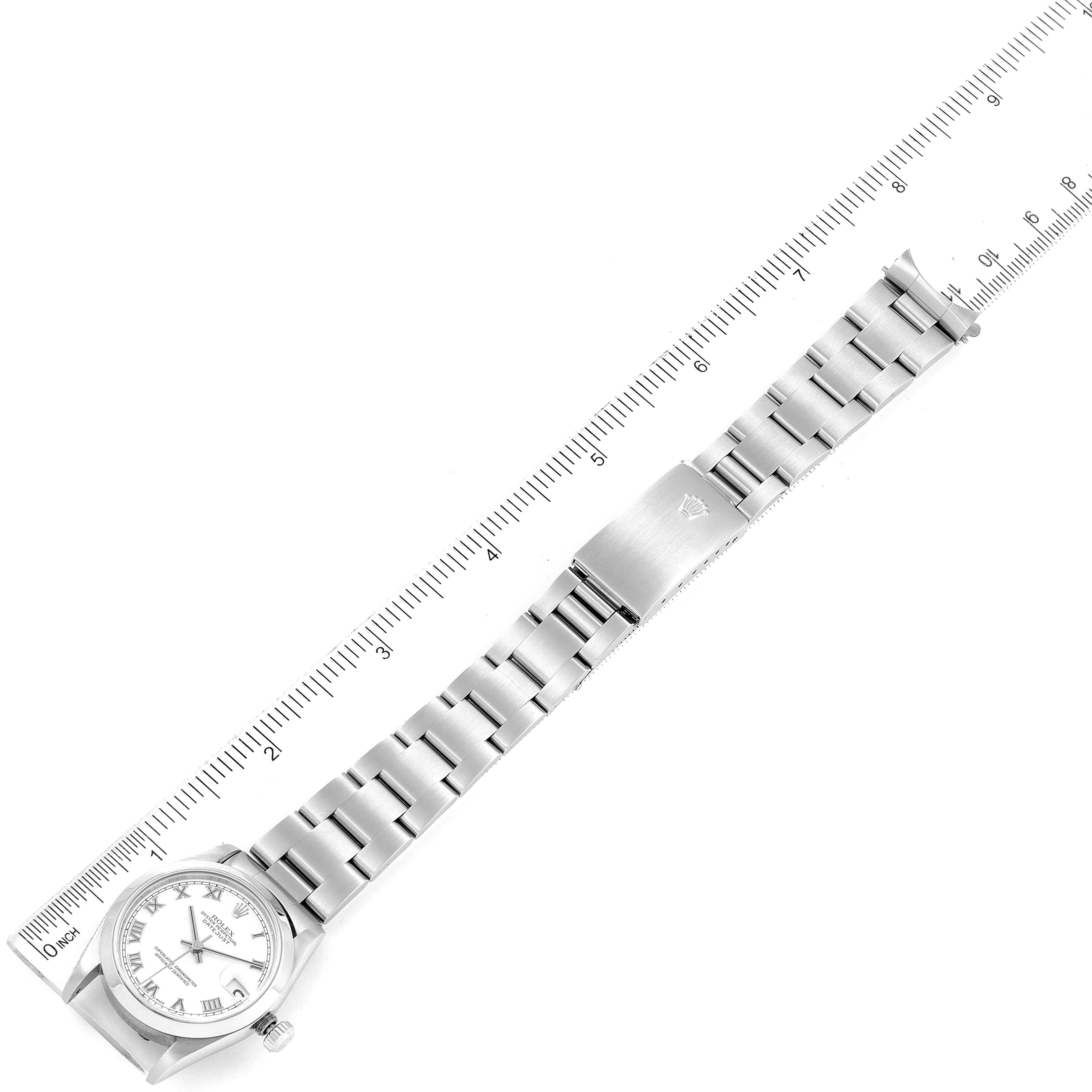 This image shows a top-down view of a Rolex Mid-Size 78240 Women
s Stainless Steel White Dial 78240 Women
s Stainless Steel White Dial model watch with its clasp and bracelet aligned to a ruler.