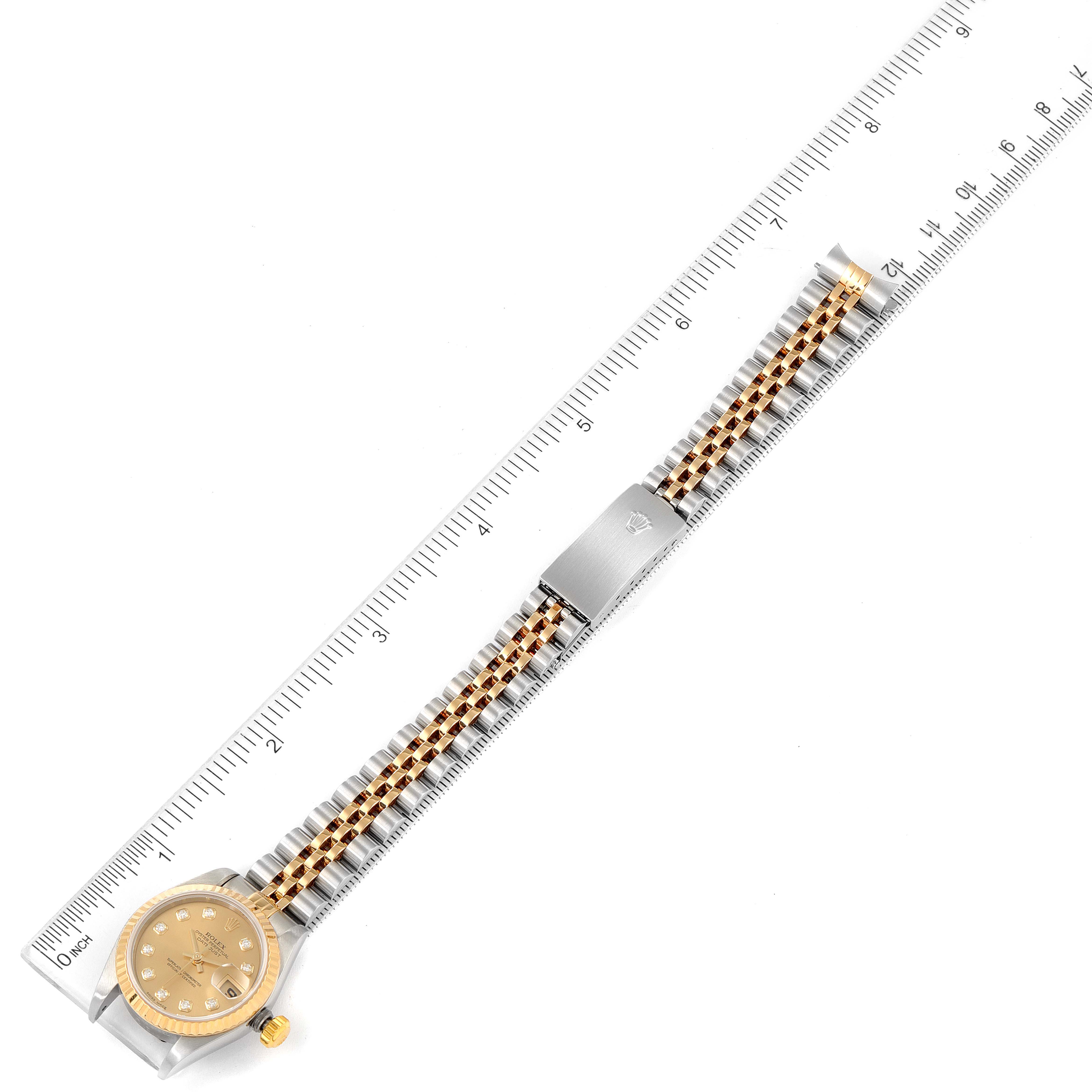 The Rolex Datejust 79173 Women
s Steel and Gold (two tone) Champagne Dial 79173 Women
s Steel and Gold (two tone) Champagne Dial watch is shown from a top-down angle, displaying the face, band, clasp, and a ruler for scale.