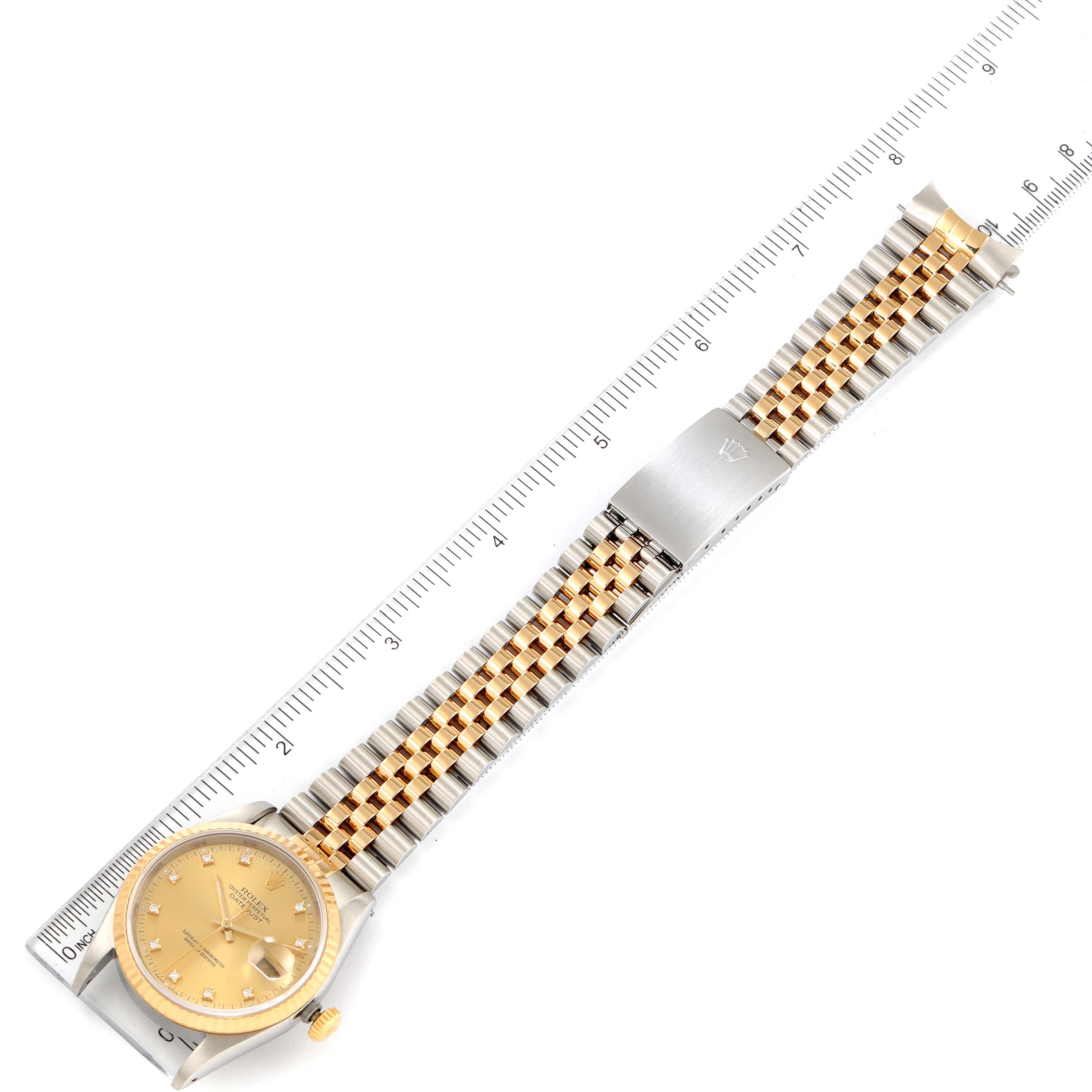 The Rolex Datejust 16233 Men's Steel and Gold (two tone) Champagne Dial 16233 Men's Steel and Gold (two tone) Champagne Dial watch is shown laying flat, highlighting the dial, bracelet, and clasp, against a ruler for measurement.