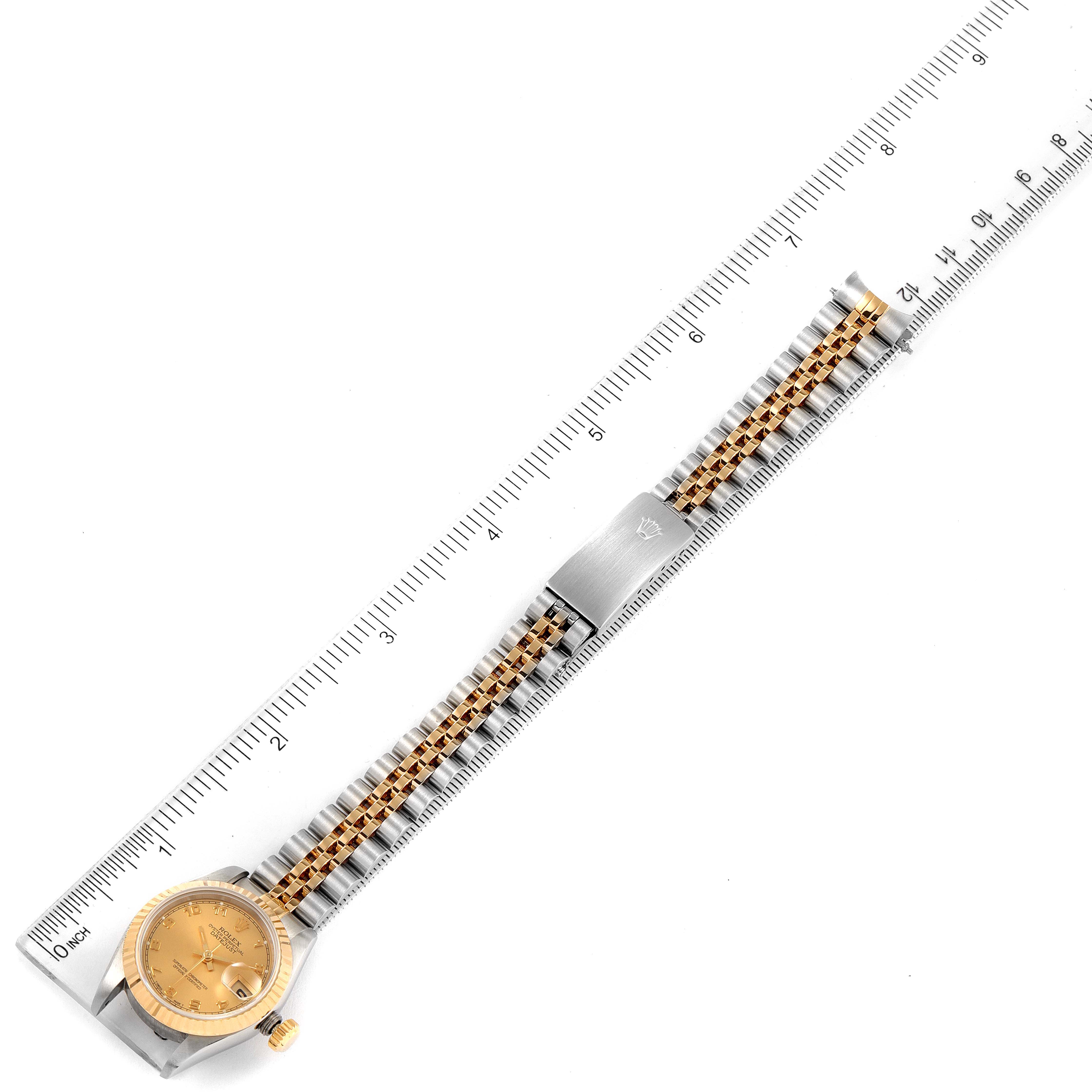The image shows a top-down view of a Rolex Datejust 69173 Women
s Steel and Gold (two tone) Champagne Dial 69173 Women
s Steel and Gold (two tone) Champagne Dial watch with a gold dial and a two-tone bracelet, aligned with a ruler.