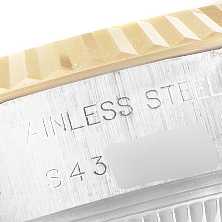 This close-up image of the Rolex Datejust 69173 Women
s Steel and Gold (two tone) Champagne Dial 69173 Women
s Steel and Gold (two tone) Champagne Dial watch shows a portion of the bezel and case with engraved text.