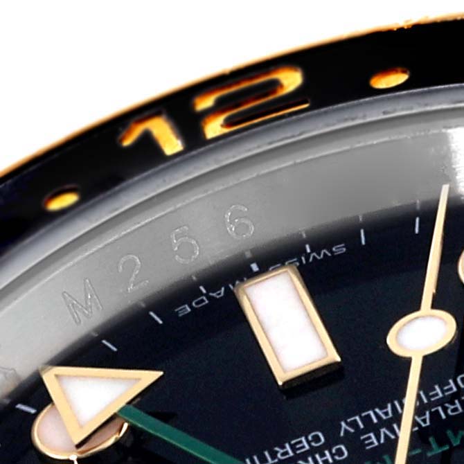 The image shows a close-up of the dial and bezel of a Rolex GMT-Master 116713 Men's Steel and Gold (two tone) Black Dial 116713 Men's Steel and Gold (two tone) Black Dial, highlighting the 12-hour marker and hour hand. 