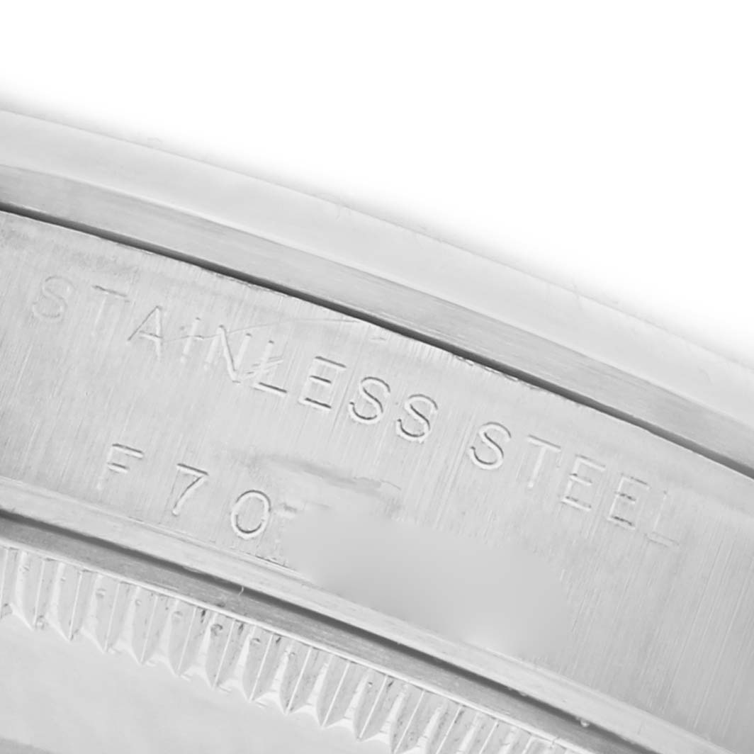 The image shows a close-up of the case back edge of a Rolex Mid-Size 77080 Women's Stainless Steel Black Dial 77080 Women's Stainless Steel Black Dial watch, highlighting the "STAINLESS STEEL" text and serial number engraving.