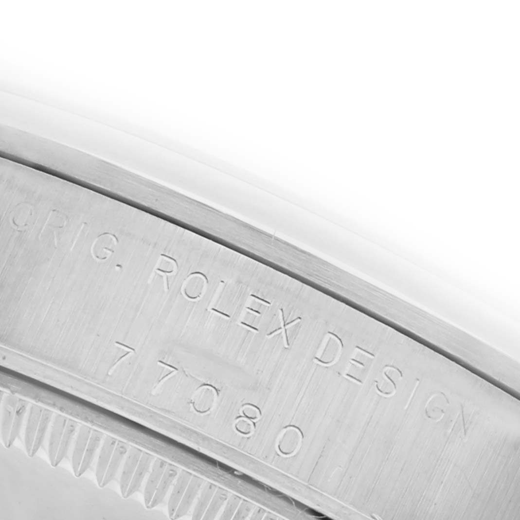 The image shows a close-up of the side of a Rolex Mid-Size 77080 Women's Stainless Steel Black Dial 77080 Women's Stainless Steel Black Dial watch, focusing on the engraved design markings and model number.