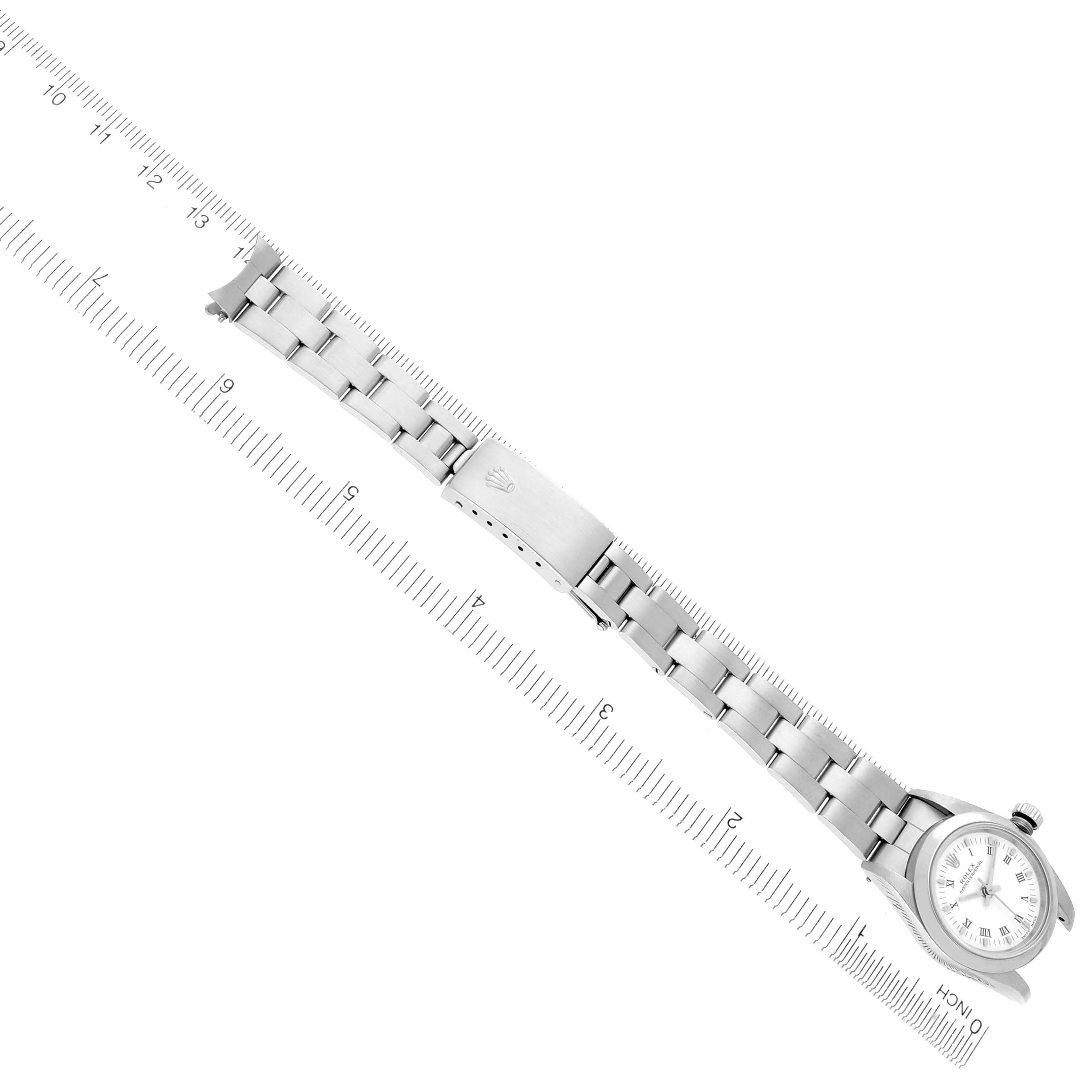 The Rolex Oyster Perpetual 76080 Women's Stainless Steel White Dial 76080 Women's Stainless Steel White Dial watch is shown from an overhead angle, displaying the bracelet and clasp alongside a measuring ruler.