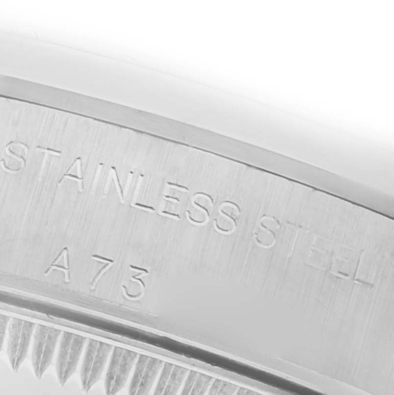 The image shows a close-up of the engraved side of the Rolex Oyster Perpetual 76080 Women's Stainless Steel White Dial 76080 Women's Stainless Steel White Dial case, featuring "STAINLESS STEEL" text.