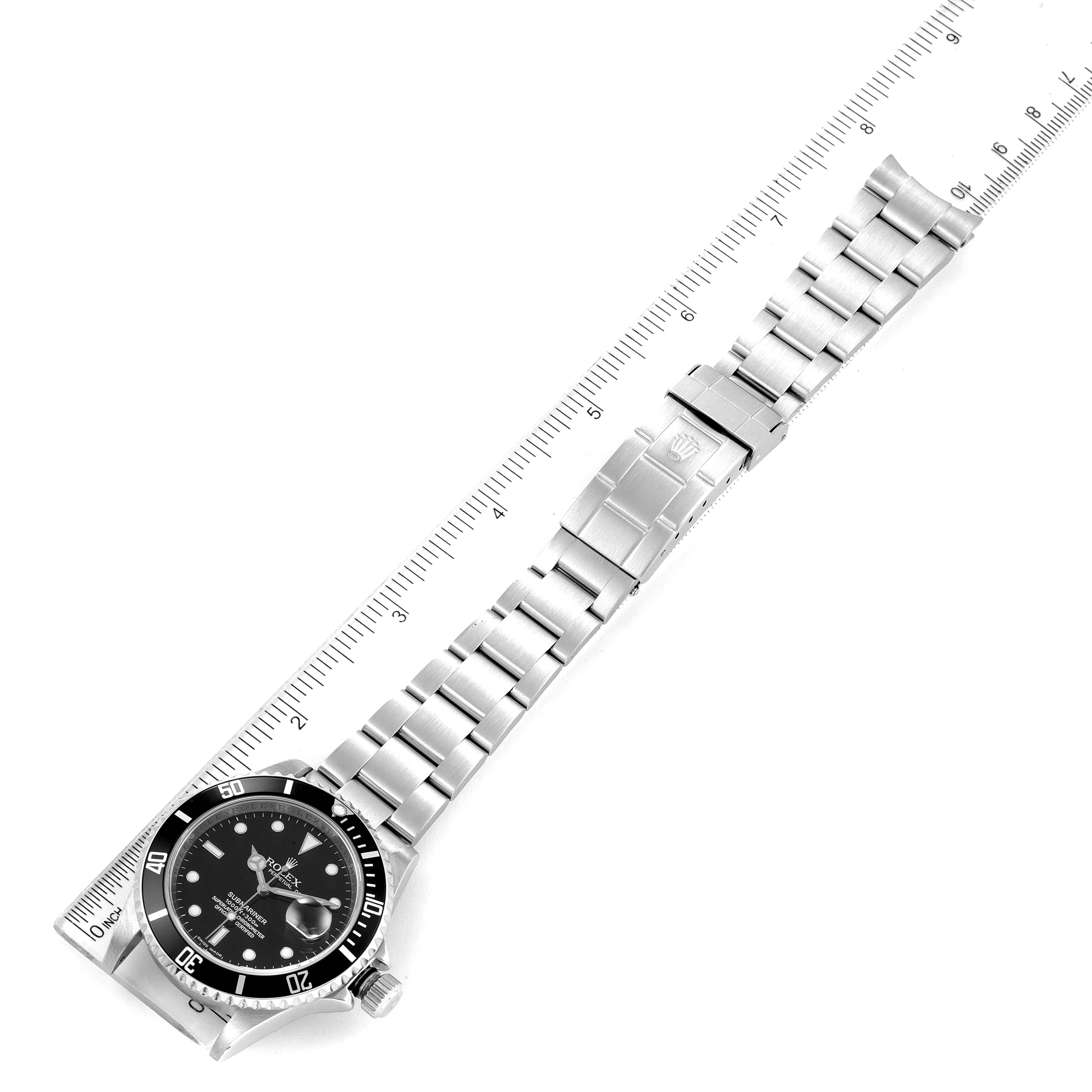 The Rolex Submariner 16610 Men
s Stainless Steel Black Dial 16610 Men
s Stainless Steel Black Dial watch is shown from the top, displaying its face, bezel, bracelet, and clasp beside a ruler for scale.