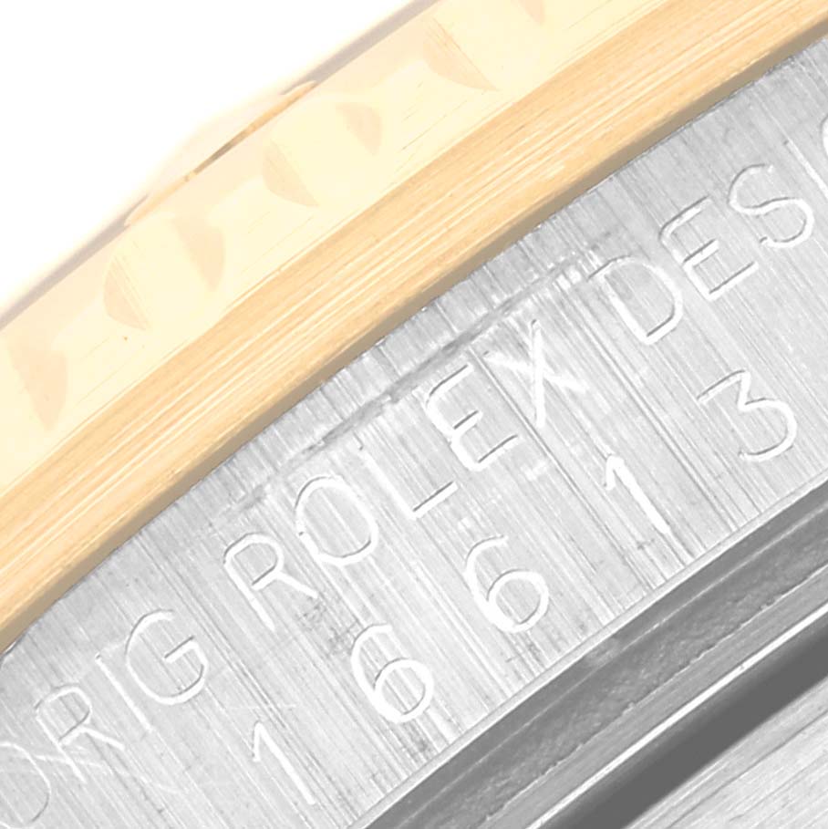 The image shows a close-up of the edge and bezel of a Rolex Submariner 16613 Men
s Steel and Gold (two tone) Blue Dial 16613 Men
s Steel and Gold (two tone) Blue Dial watch, highlighting the engraved model number.