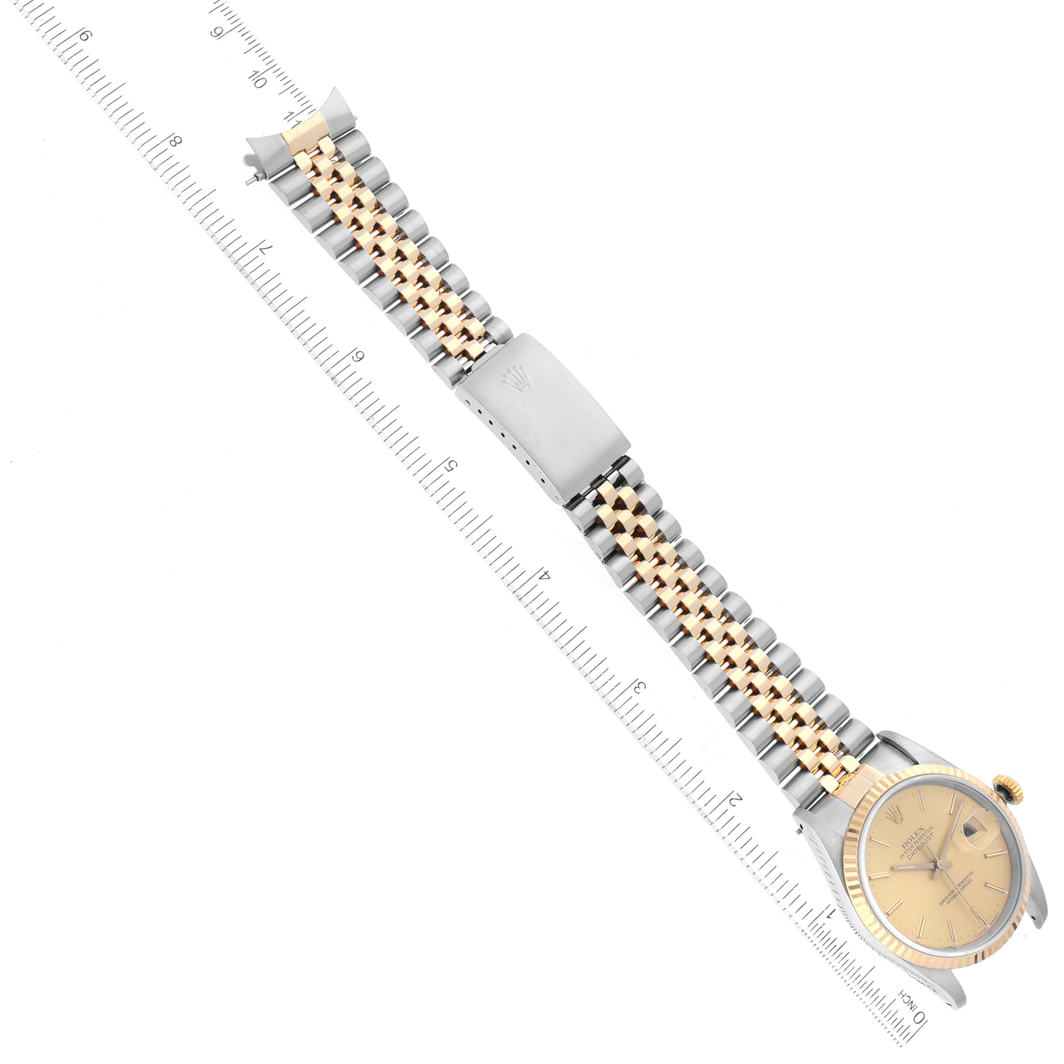 This Rolex Datejust 16233 Men's Steel and Gold (two tone) Champagne Dial 16233 Men's Steel and Gold (two tone) Champagne Dial watch is shown from a top-down angle displaying its face, bracelet, and clasp, alongside a ruler.