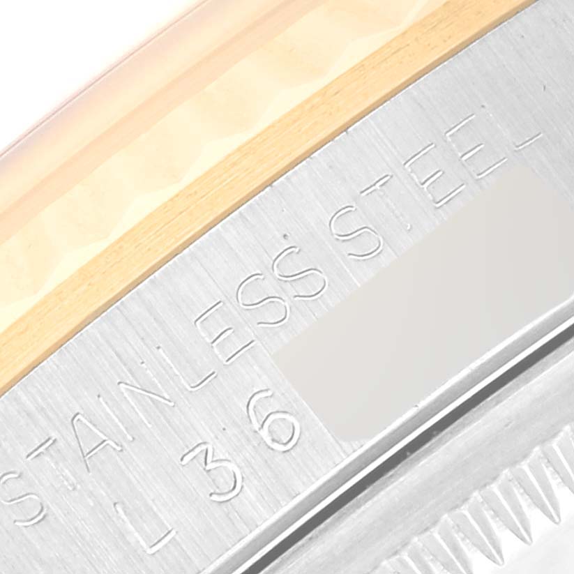 The image shows a close-up section of a stainless steel part of a Rolex Datejust 16233 Men's Steel and Gold (two tone) Champagne Dial 16233 Men's Steel and Gold (two tone) Champagne Dial watch with engraved text and partial bezel.