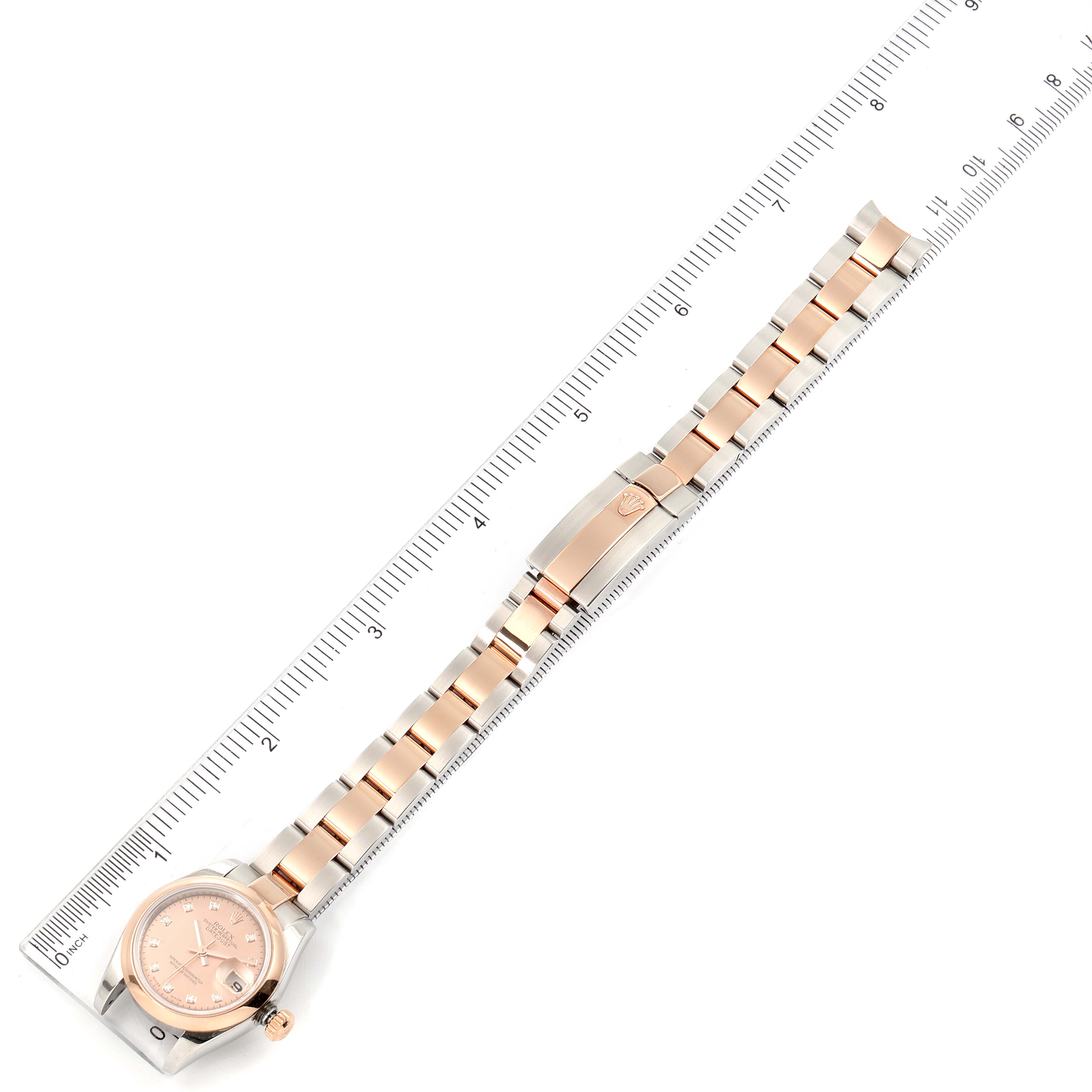 The Rolex Datejust 179161 Women's Rose Gold Pink Dial 179161 Women's Rose Gold Pink Dial watch is shown from above, displaying its face, bracelet, and clasp, alongside a measurement scale.