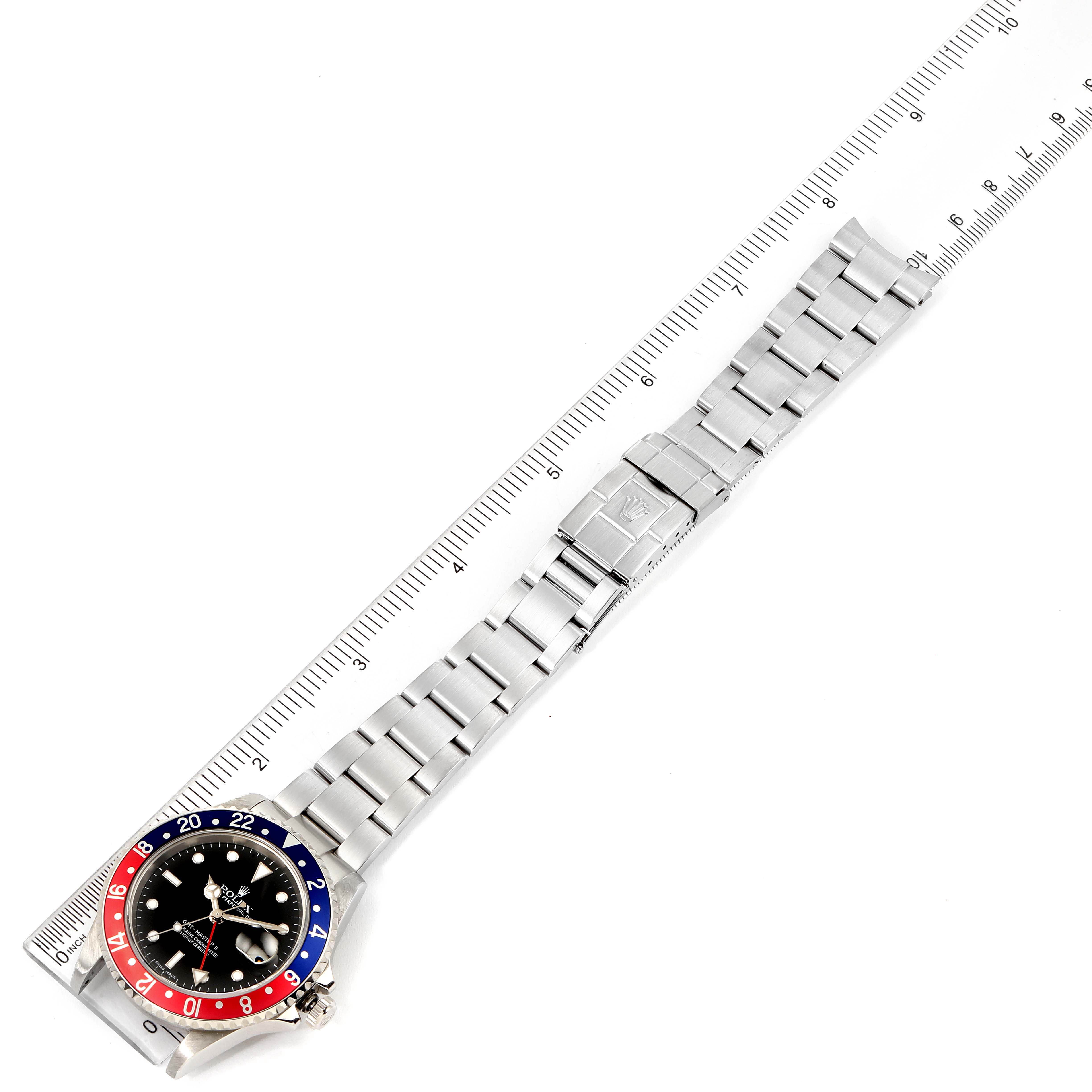 The image shows a Rolex GMT-Master 16710 Men's Stainless Steel Black Dial 16710 Men's Stainless Steel Black Dial watch laid flat with its stainless steel bracelet fully extended alongside a ruler for scale.
