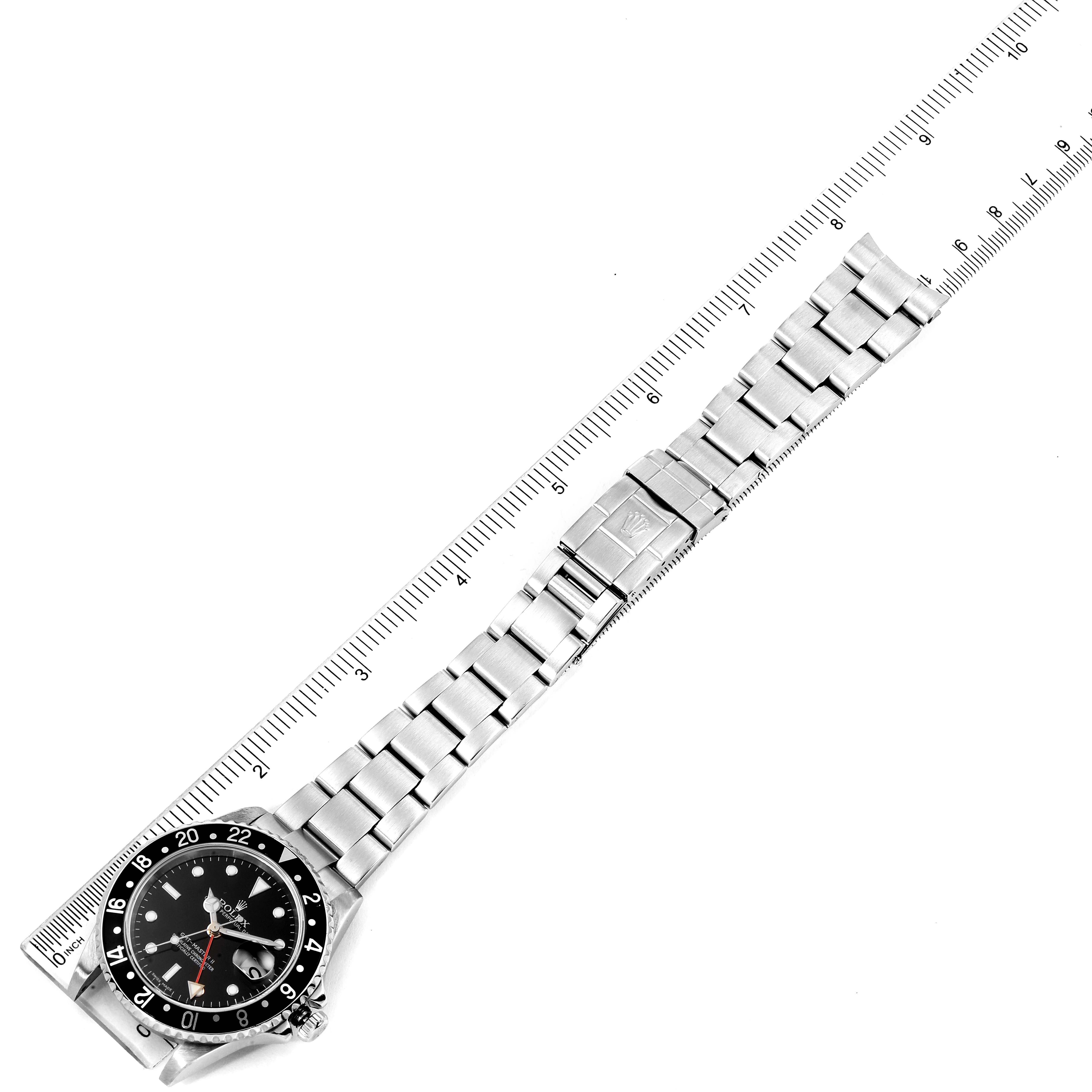 The image shows a top-down view of the Rolex GMT-Master 16710 Men's Stainless Steel Black Dial 16710 Men's Stainless Steel Black Dial watch, highlighting the face, bezel, and metal bracelet with a ruler for scale.
