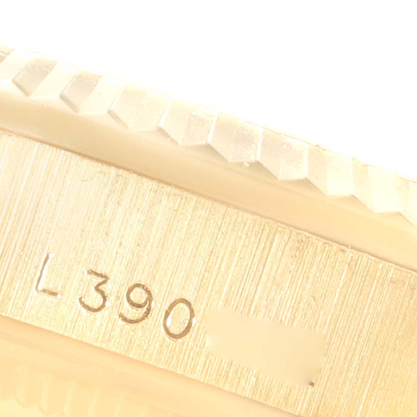 This close-up image shows a partial view of the Rolex President 68278 Women
s Yellow Gold Champagne Dial 68278 Women
s Yellow Gold Champagne Dial model
s fluted bezel and inscribed serial number.