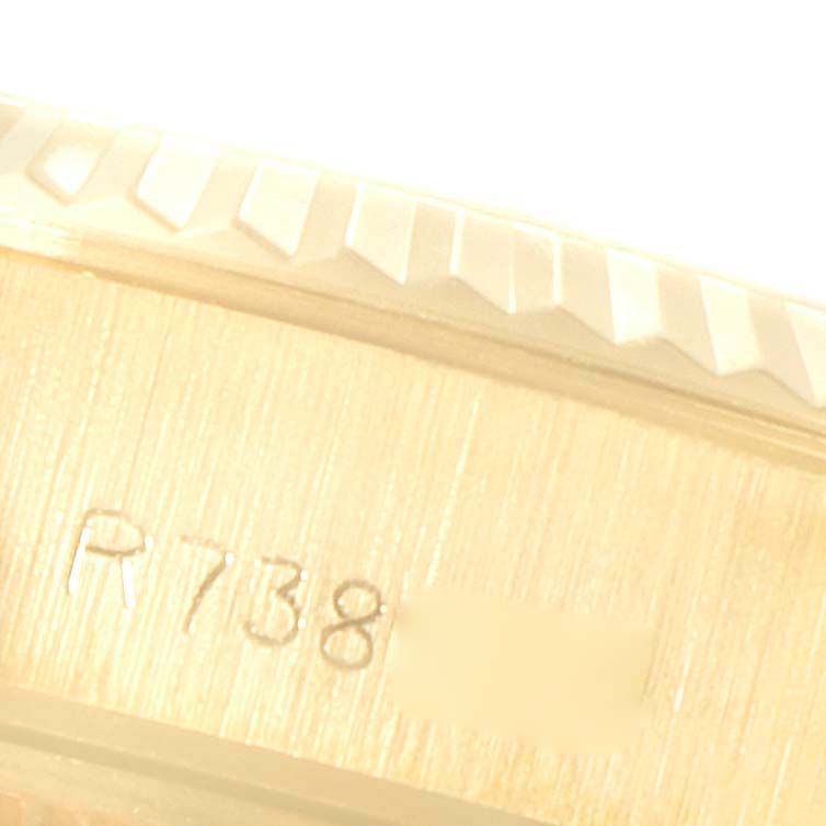 This close-up image of a Rolex President 69178 Women's Yellow Gold Champagne Dial 69178 Women's Yellow Gold Champagne Dial model watch shows the serial number engraved on the case and a portion of the fluted bezel.