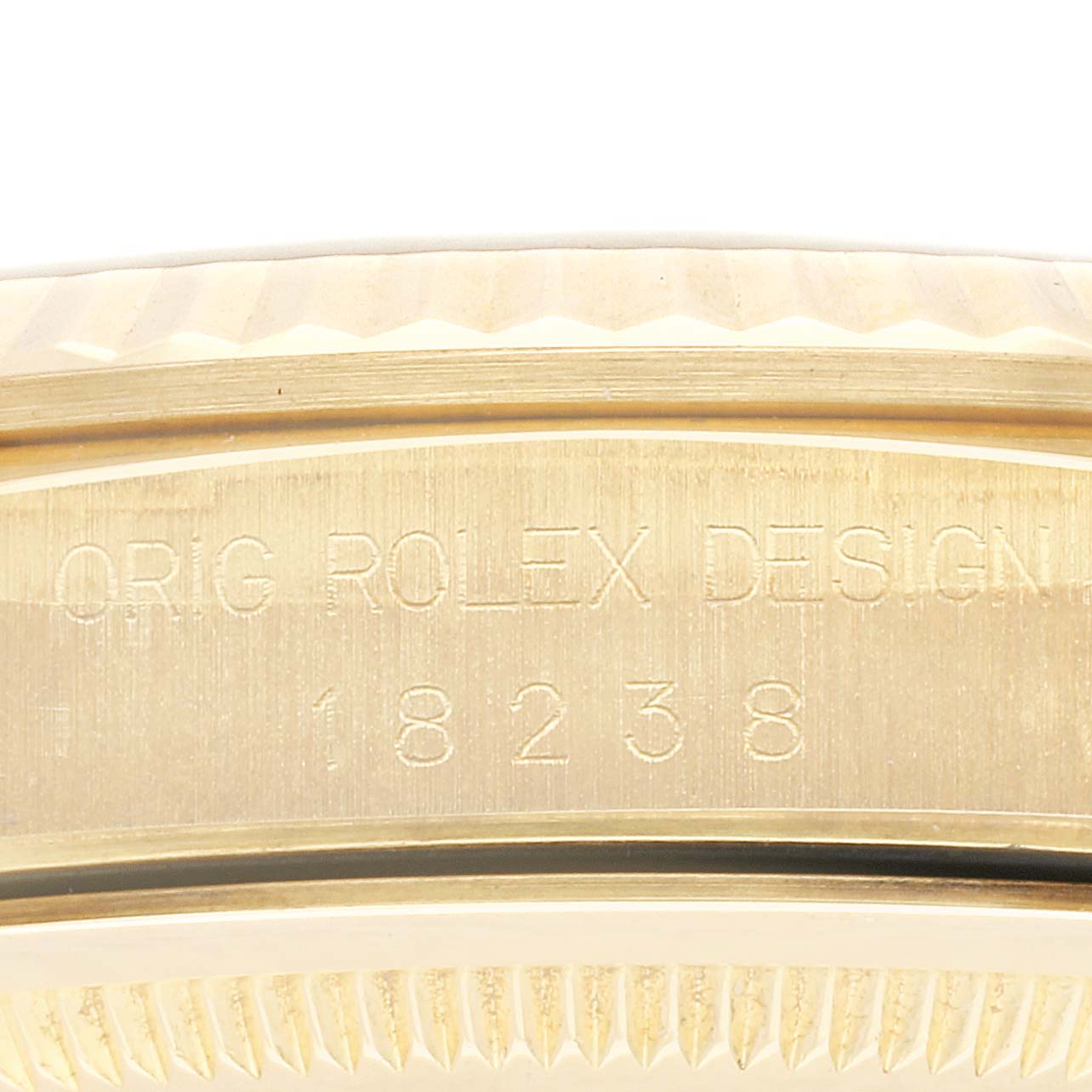 The image shows a close-up detail of the side of a Rolex President 18238 Men
s Yellow Gold Champagne Dial 18238 Men
s Yellow Gold Champagne Dial model, displaying its serial number and "ORIG ROLEX DESIGN" engraving.