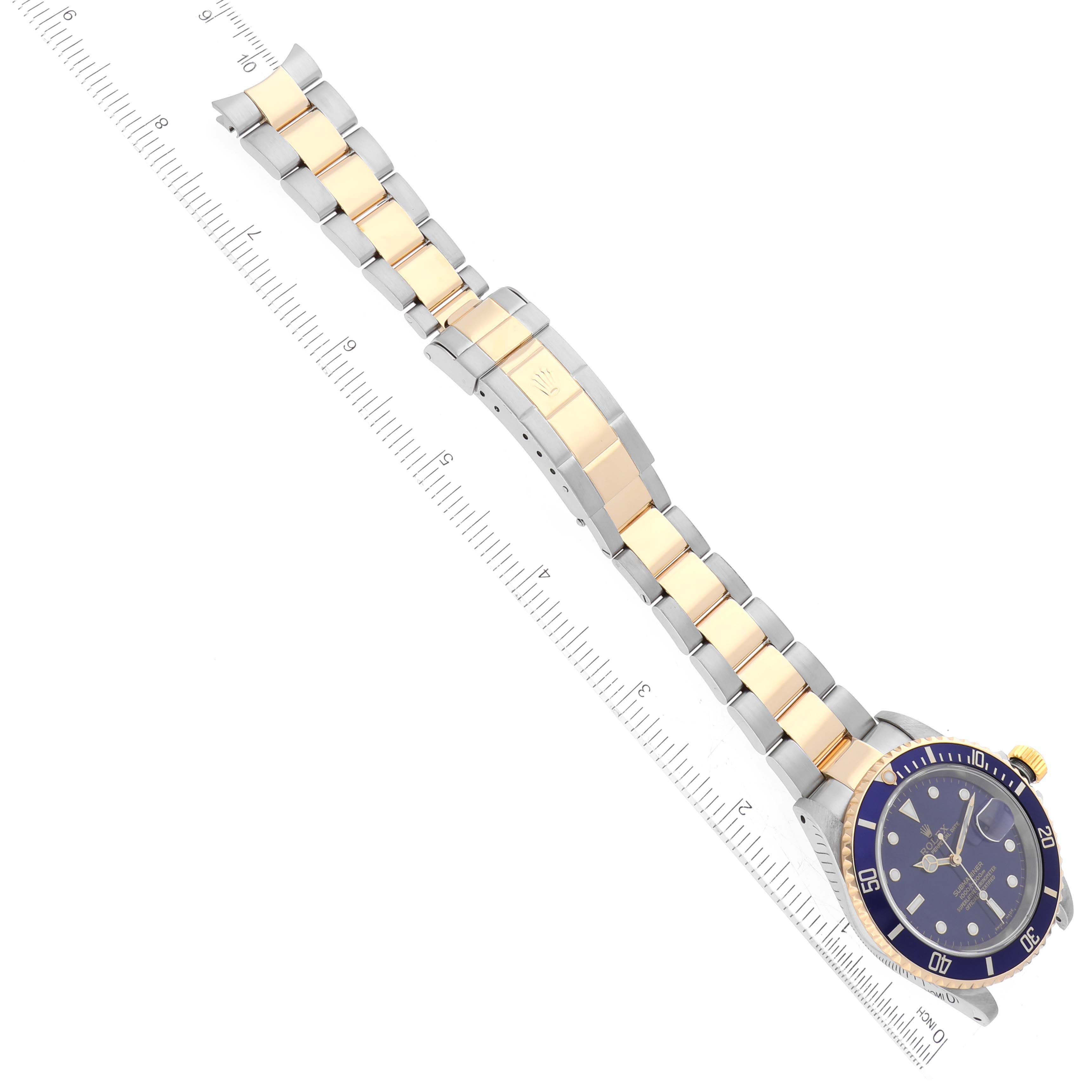 The image shows a Rolex Submariner 16613 Men's Steel and Gold (two tone) Blue Dial 16613 Men's Steel and Gold (two tone) Blue Dial watch placed diagonally, highlighting the face and metal bracelet with gold center links.
