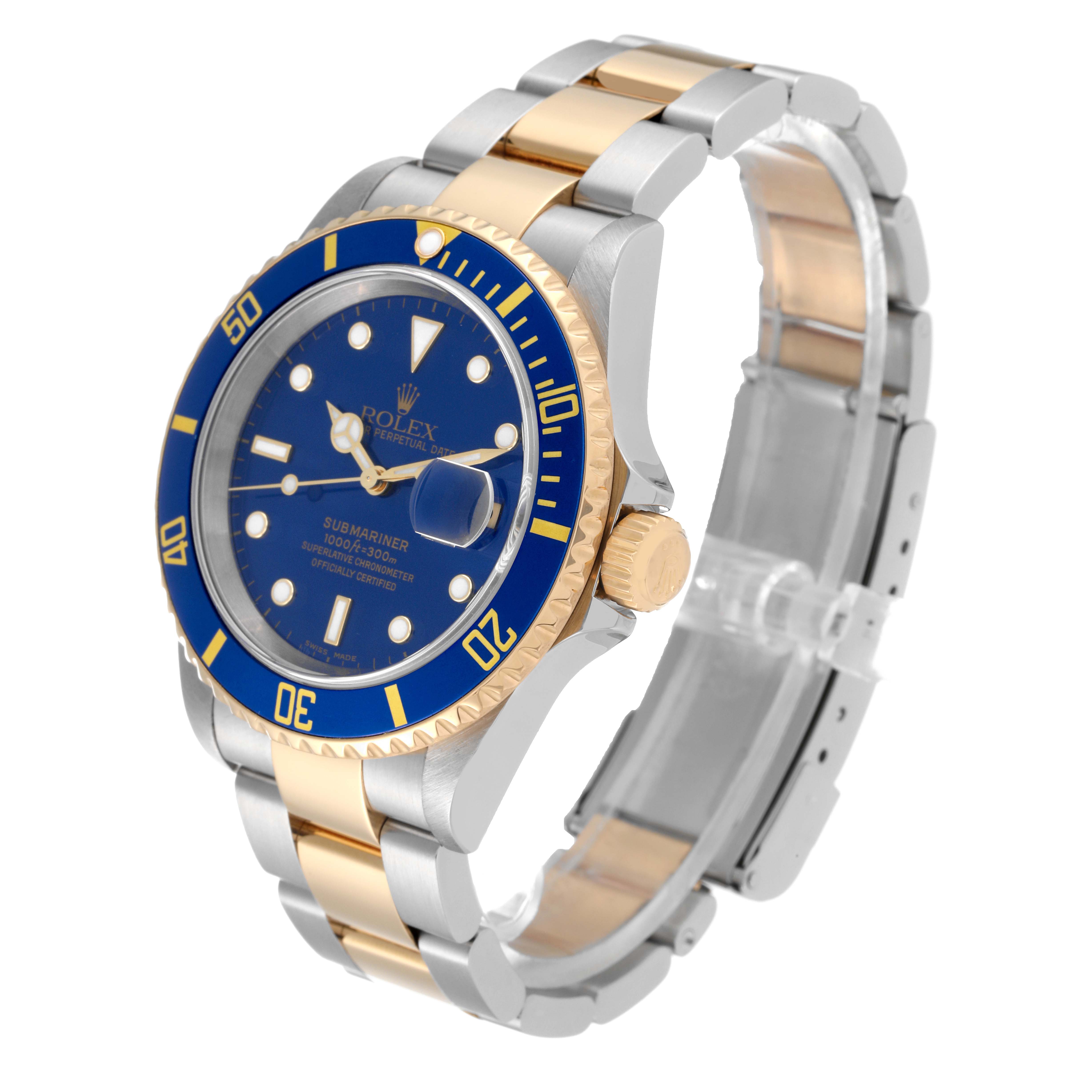 The image shows a Rolex Submariner 16613T Men
s Steel and Gold (two tone) Blue Dial 16613T Men
s Steel and Gold (two tone) Blue Dial watch at an angle displaying the face, bezel, crown, and the two-tone bracelet.