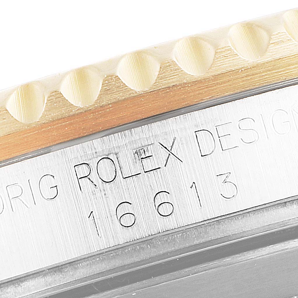 The image shows a close-up of the side of a Rolex Submariner 16613 Men
s Steel and Gold (two tone) Blue Dial 16613 Men
s Steel and Gold (two tone) Blue Dial watch, focusing on the model number 16613 and part of the bezel.