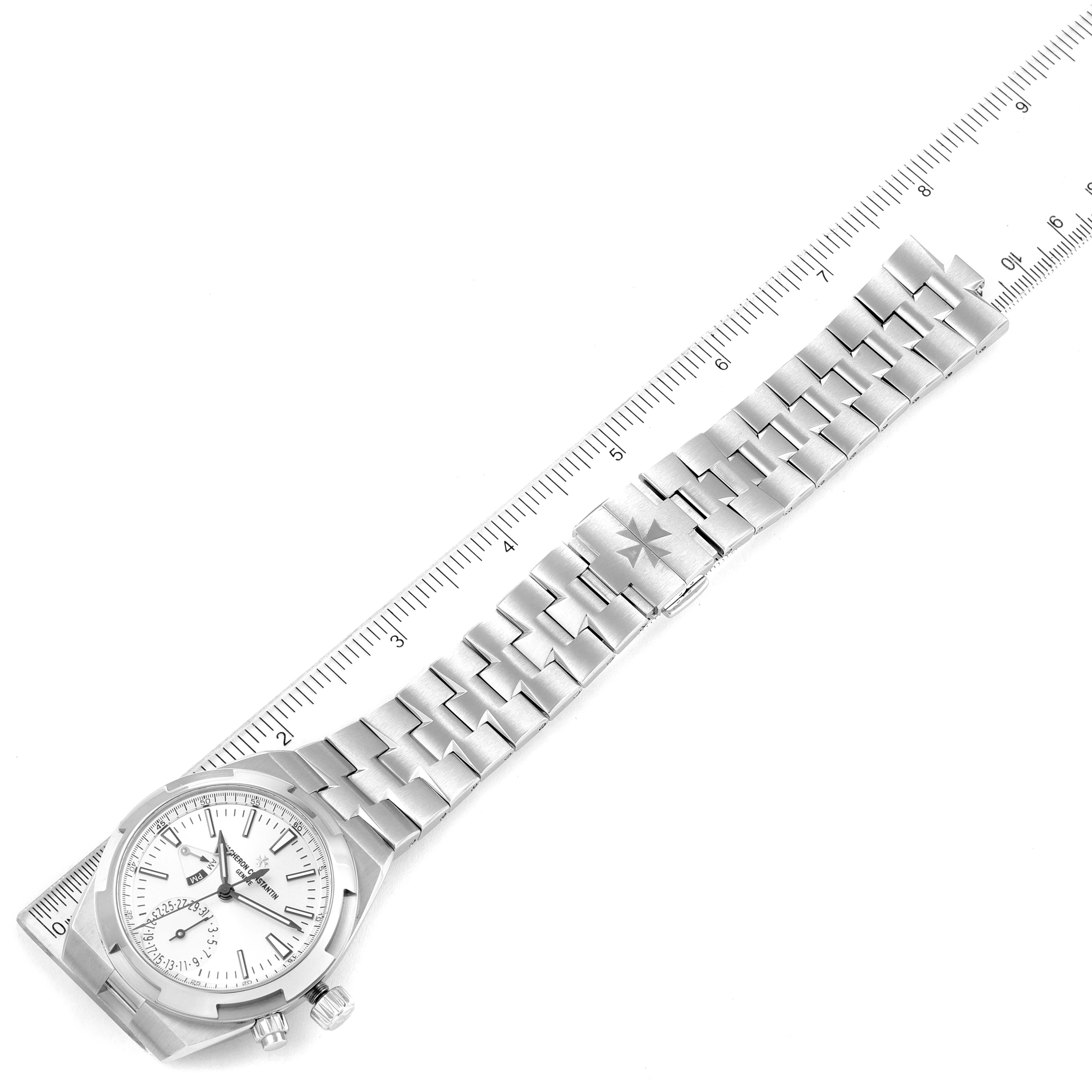 The image shows a Vacheron Constantin Overseas 7900V/110A-B333 Men's Stainless Steel Silver Dial 7900V/110A-B333 Men's Stainless Steel Silver Dial watch laid flat next to a ruler, highlighting the bracelet and watch face.