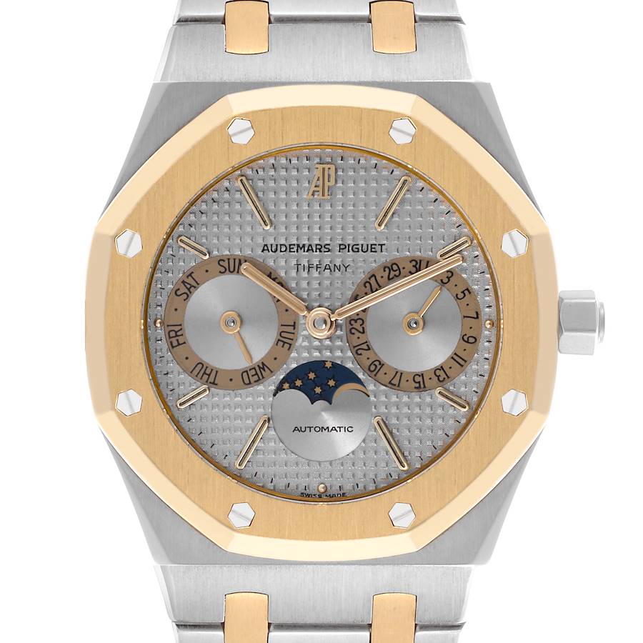 The image shows a front view of an Audemars Piguet Royal Oak with gold bezel, day, date, and moon phase indicators on the dial.