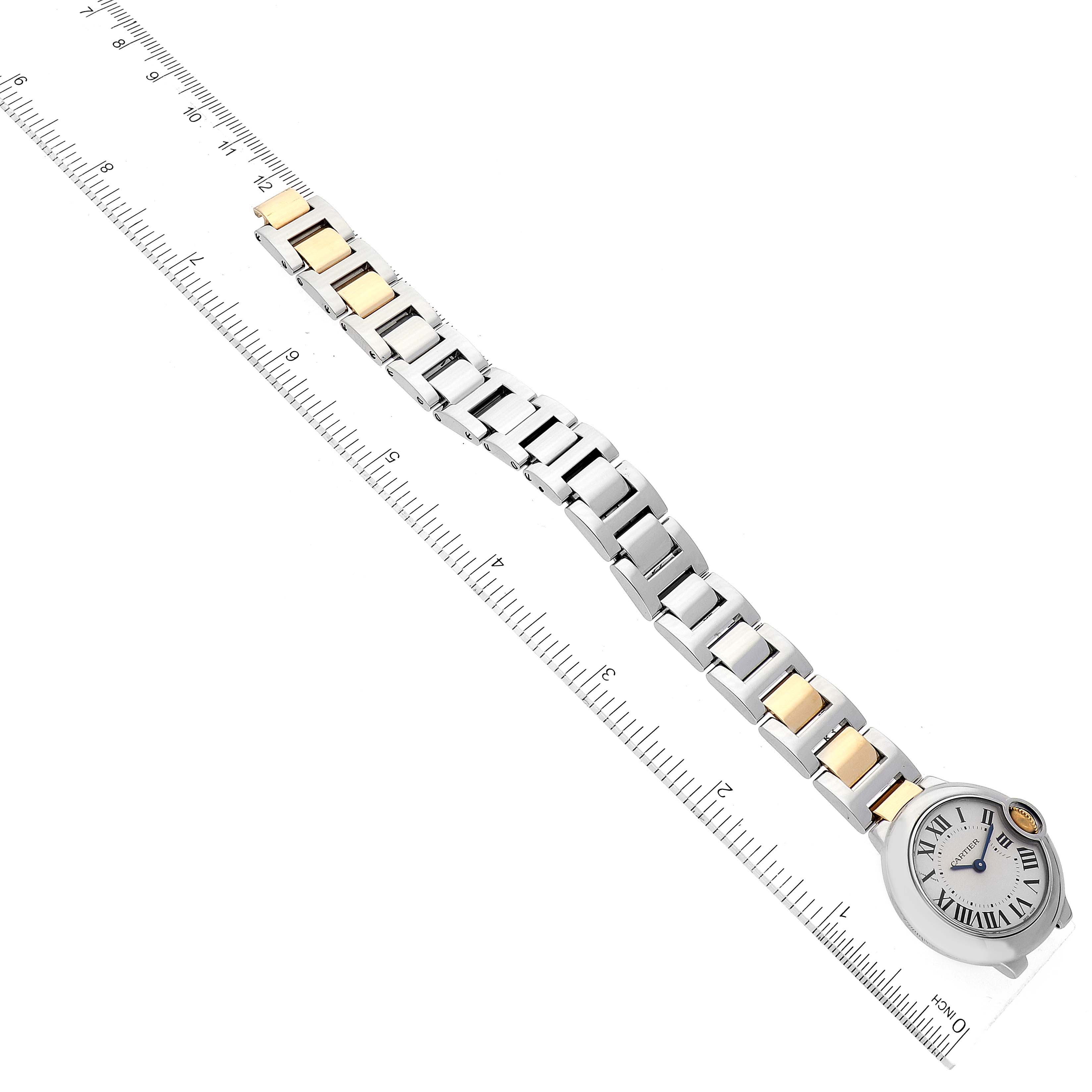 The image shows a Ballon Bleu model by Cartier, featuring the watch dial and its metal bracelet, laid next to a ruler for measurement.