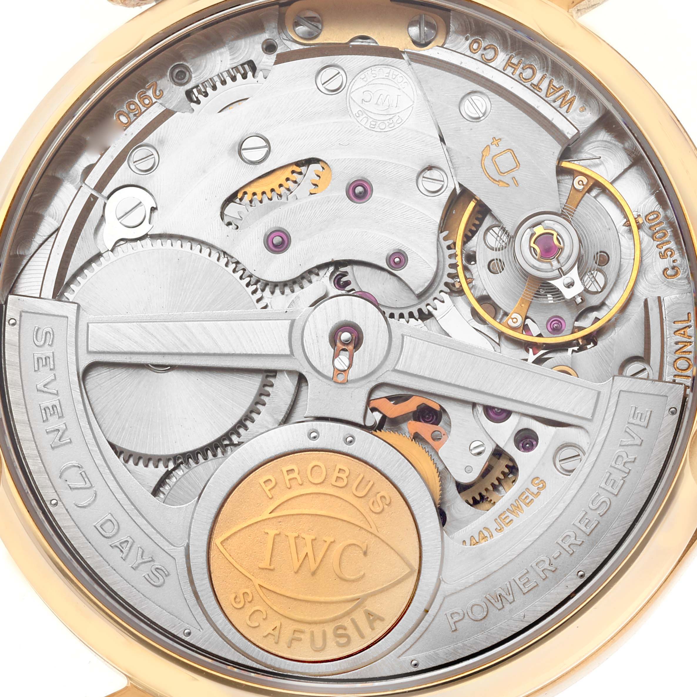 The image shows the back view of an IWC Portuguese IW500701 Men's Rose Gold Silver Dial IW500701 Men's Rose Gold Silver Dial watch, highlighting its intricate mechanical movement and branding.