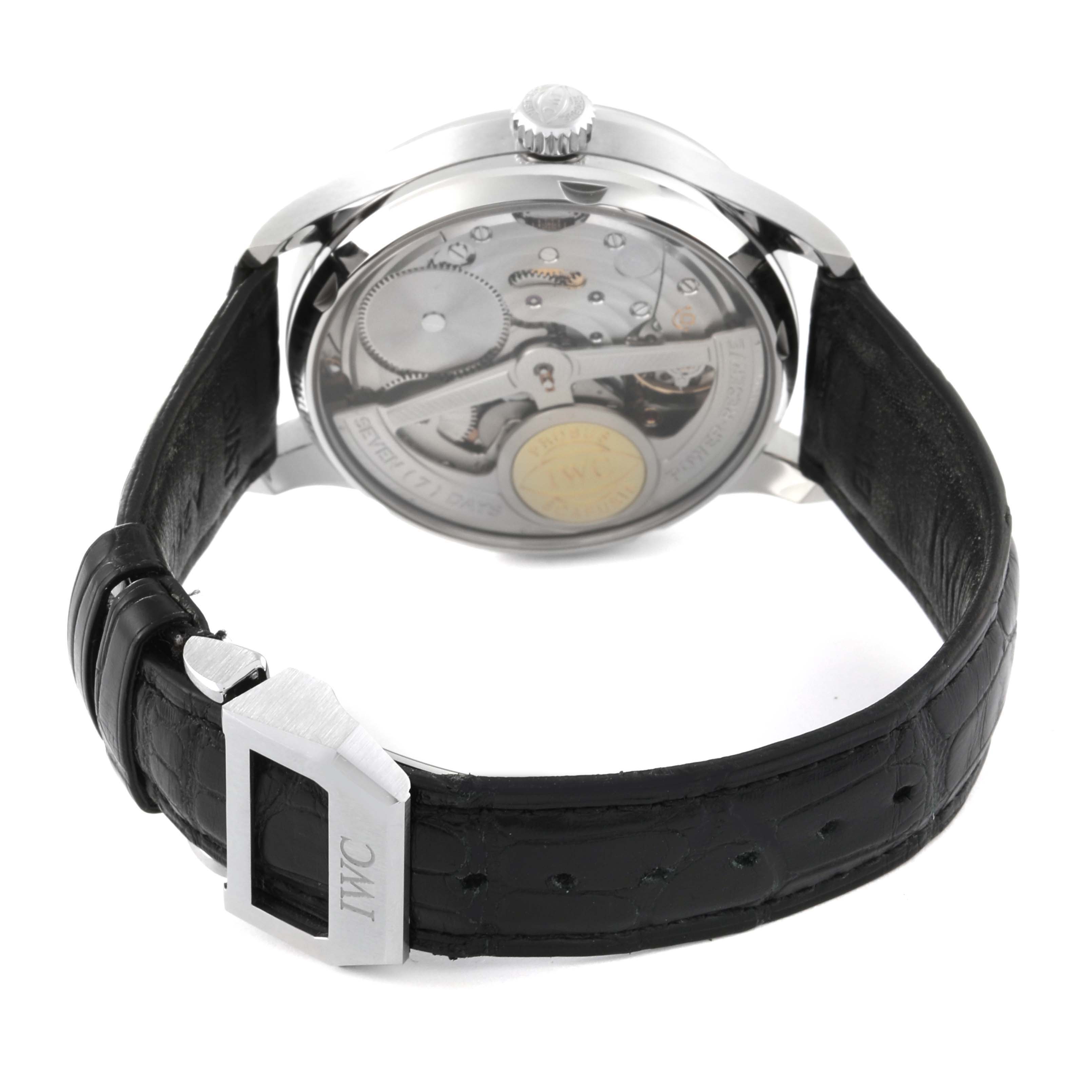 This image shows the back view of an IWC Portuguese IW500107 Men's Stainless Steel Silver Dial IW500107 Men's Stainless Steel Silver Dial model watch, highlighting its inner mechanics and leather strap with the clasp.