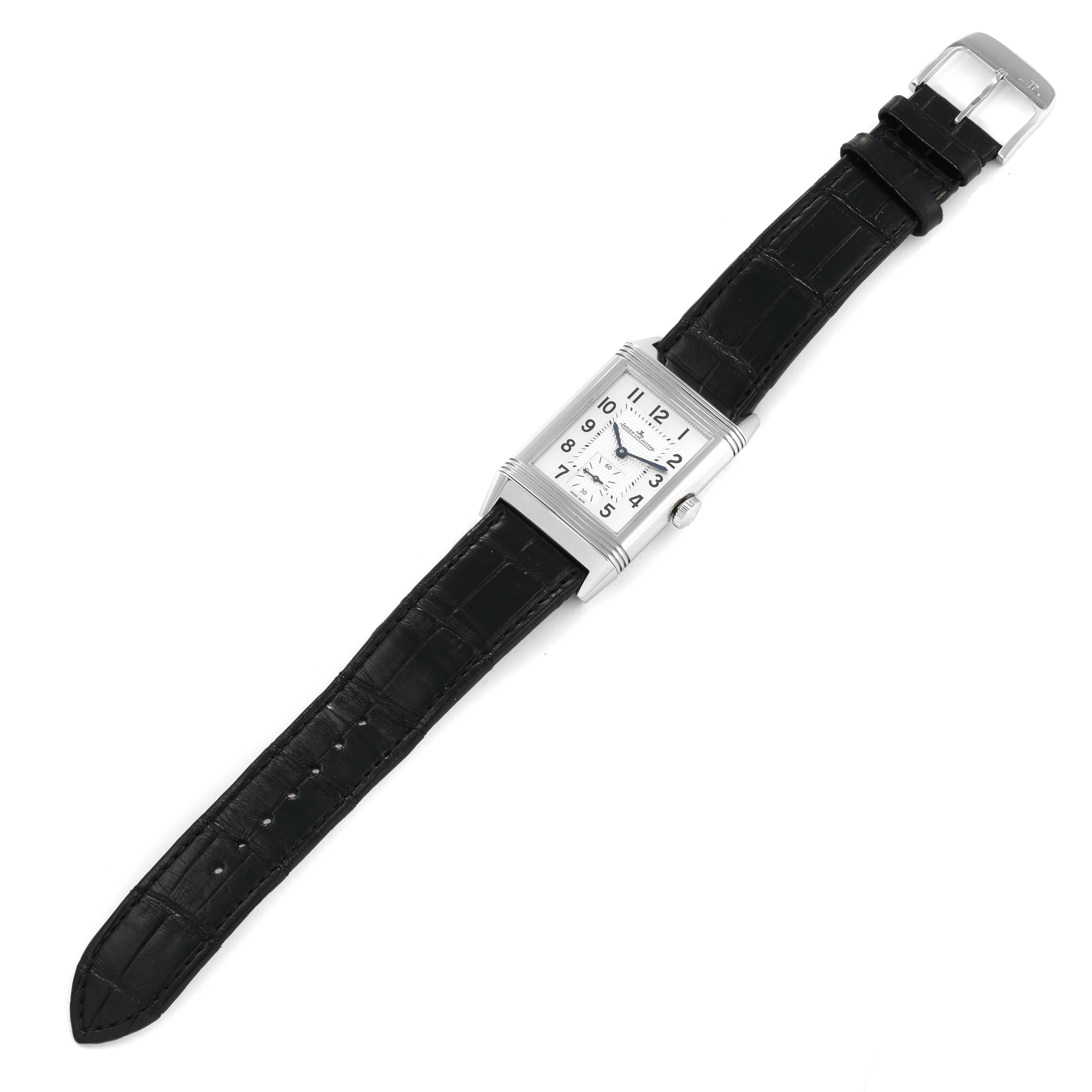 The image shows a Reverso model by Jaeger LeCoultre, featuring a rectangular case, black leather strap, and visible dial from a top-down angle.