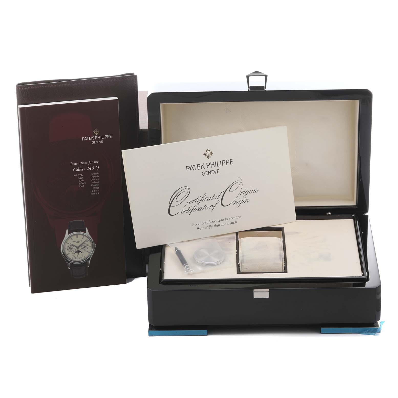 The image shows a Patek Philippe Calatrava 5140G-001 Men's White Gold Silver Dial 5140G-001 Men's White Gold Silver Dial watch box at an angle with its certificate, manual, and some accessories displayed.