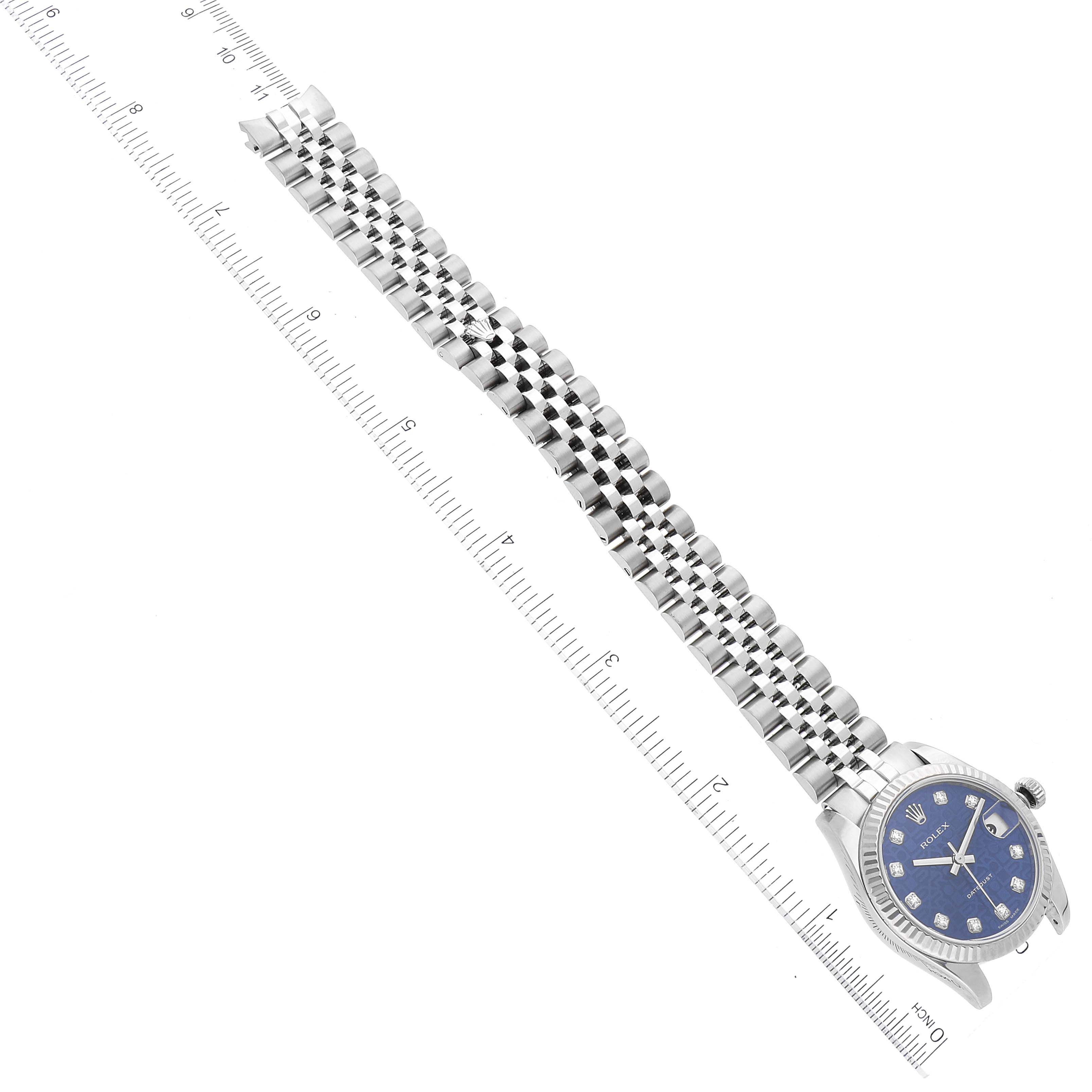 The image shows a full view of a Rolex Mid-Size 178274 Women's Stainless Steel Blue Dial 178274 Women's Stainless Steel Blue Dial watch with a blue dial and a silver link bracelet, placed beside a ruler for scale.