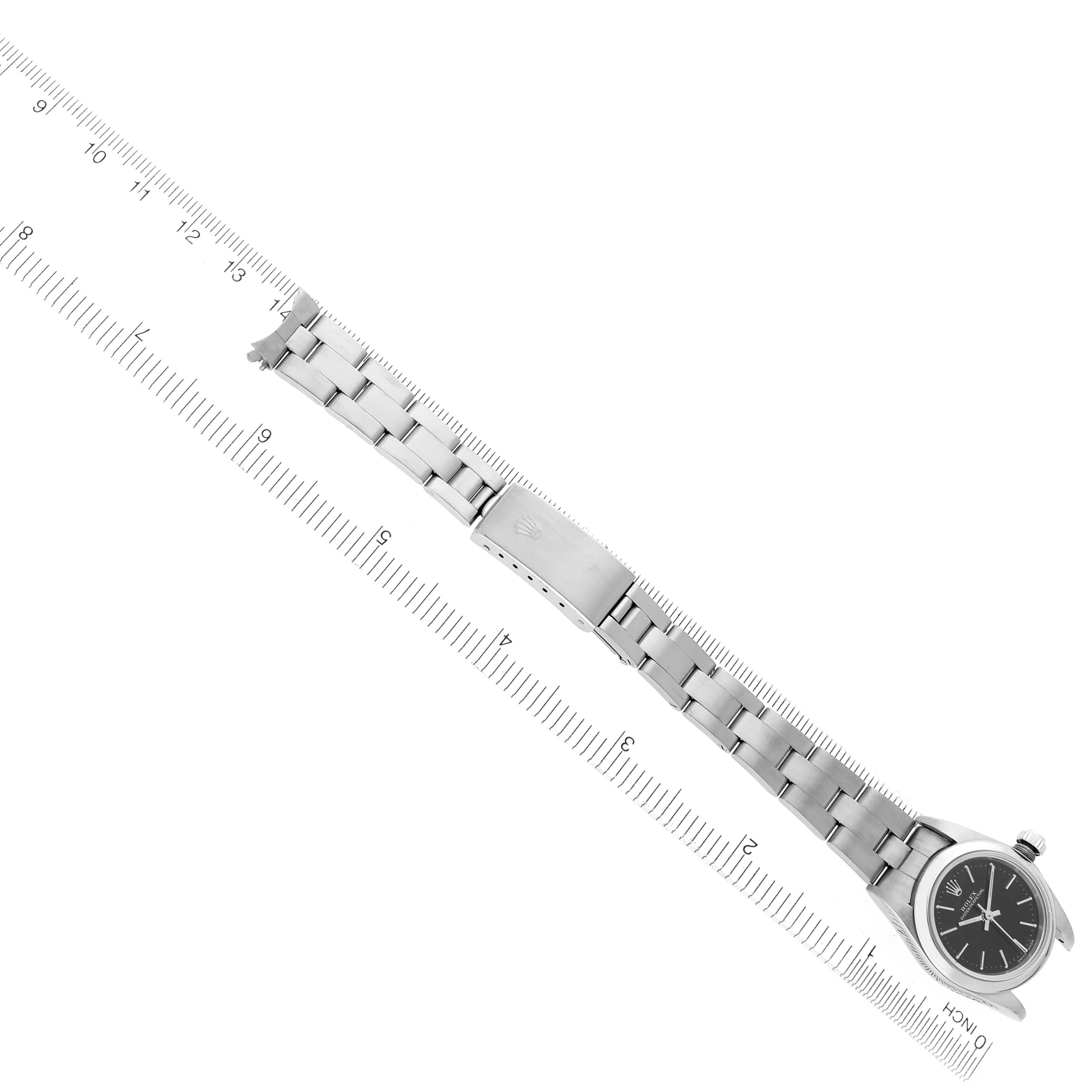 The image shows a top-down view of a Rolex Oyster Perpetual 76080 Women's Stainless Steel Black Dial 76080 Women's Stainless Steel Black Dial watch laid alongside a ruler, displaying its bracelet and clasp.
