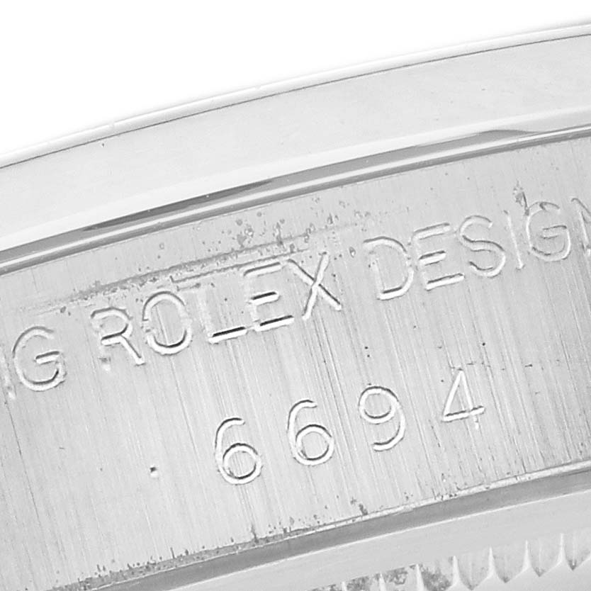 The image shows the engraved side of a Rolex Date 6694 Men's Stainless Steel Silver Dial 6694 Men's Stainless Steel Silver Dial model, featuring the design and model number.