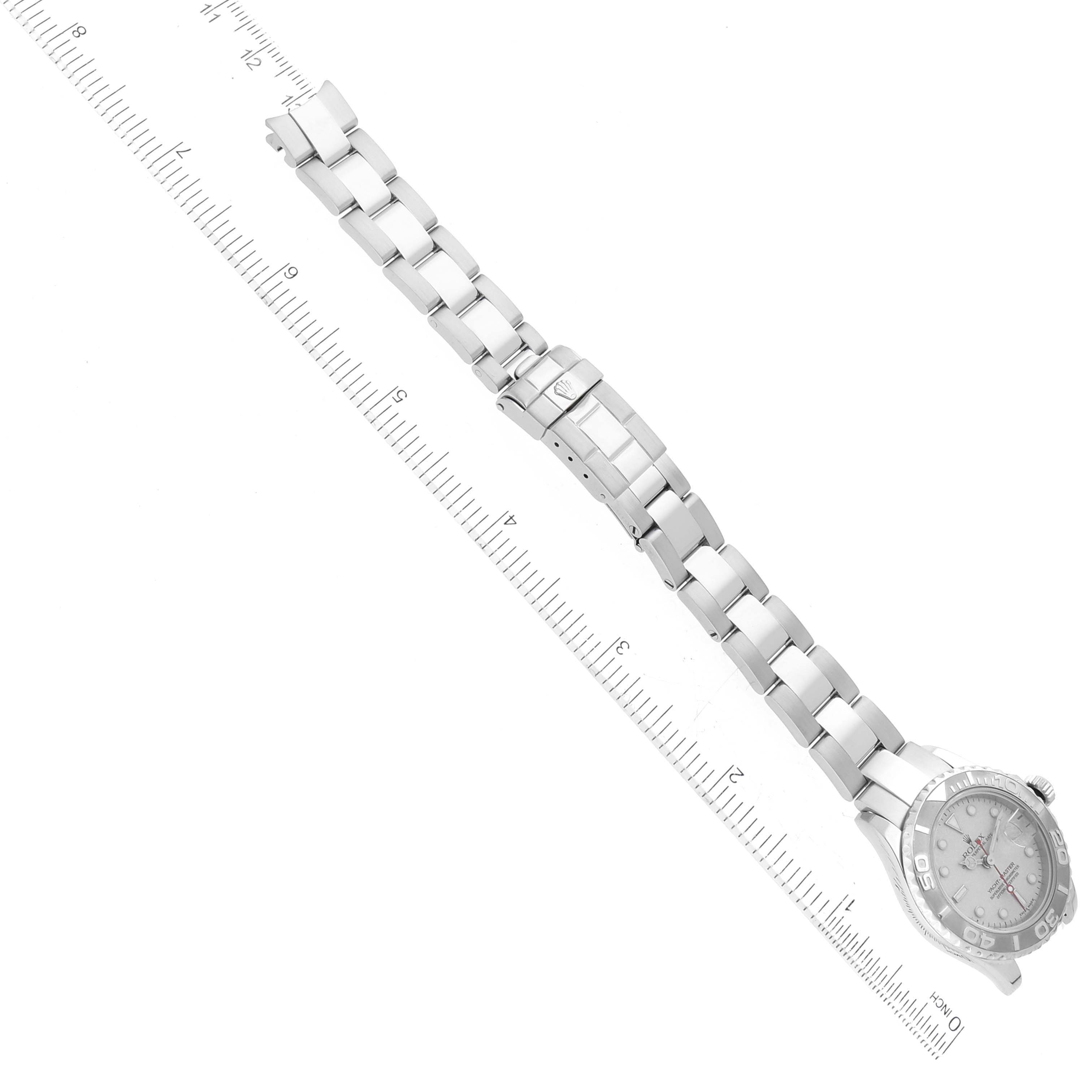 This image shows the Rolex Yacht-Master 169622 Women
s Stainless Steel Silver Dial 169622 Women
s Stainless Steel Silver Dial watch from an aerial view, focusing on the bracelet and clasp, with a ruler for scale.