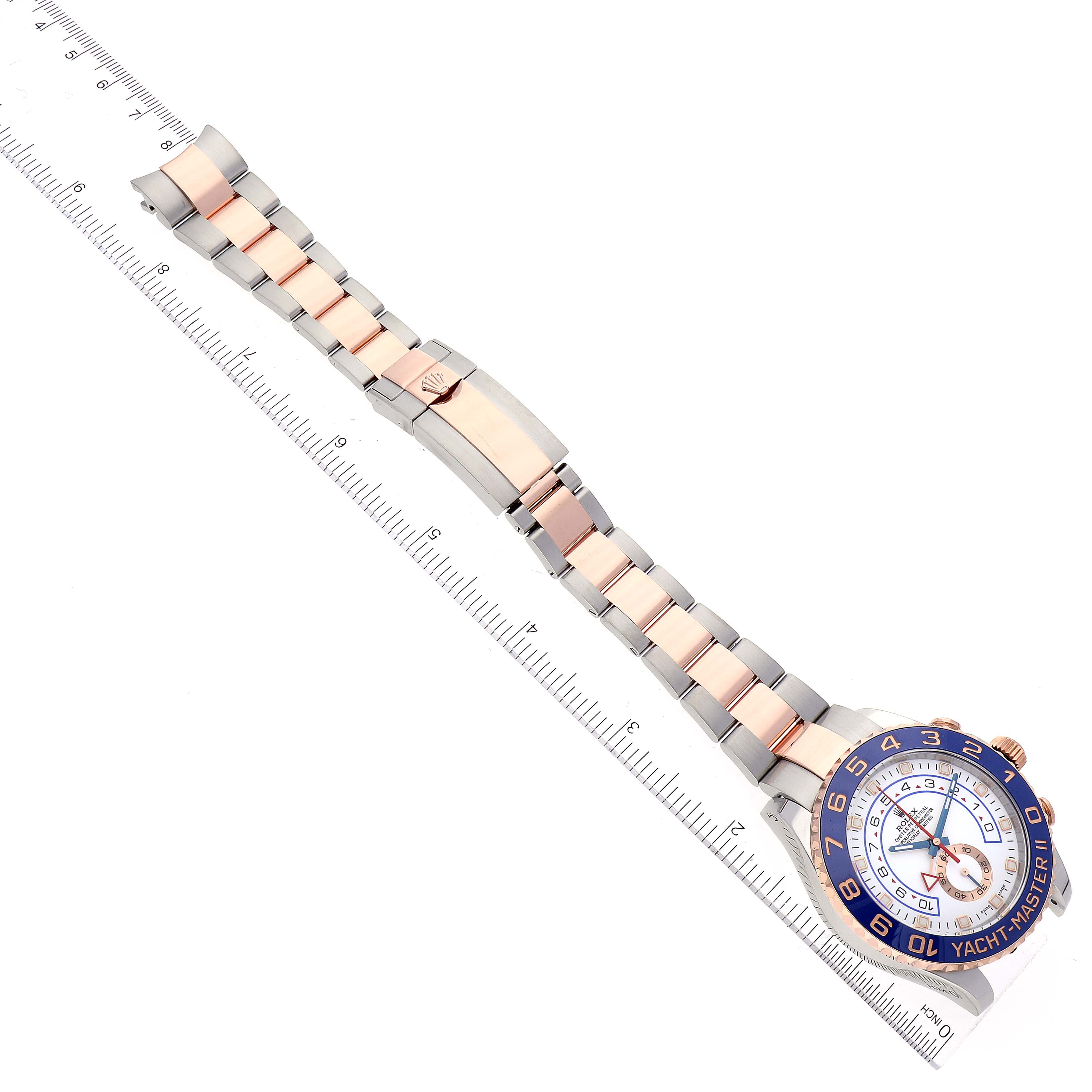 The image shows a top-down view of a Rolex Yacht-Master 116681 Men's Steel and Gold (two tone) White Dial 116681 Men's Steel and Gold (two tone) White Dial watch, highlighting its band, clasp, and face, next to a ruler.