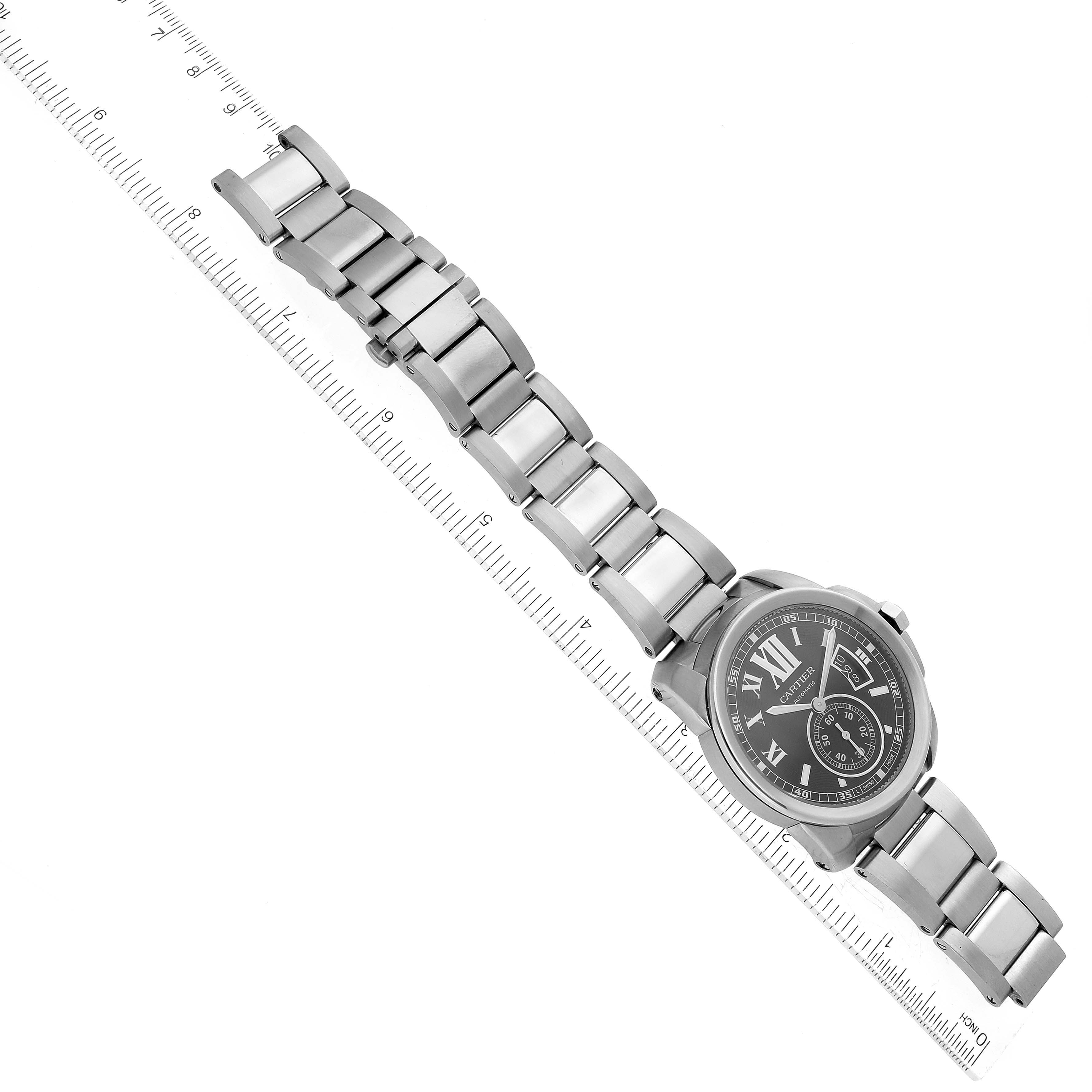 The image shows a top view of a Calibre de Cartier watch by Cartier with its metal bracelet fully extended, placed next to a ruler.